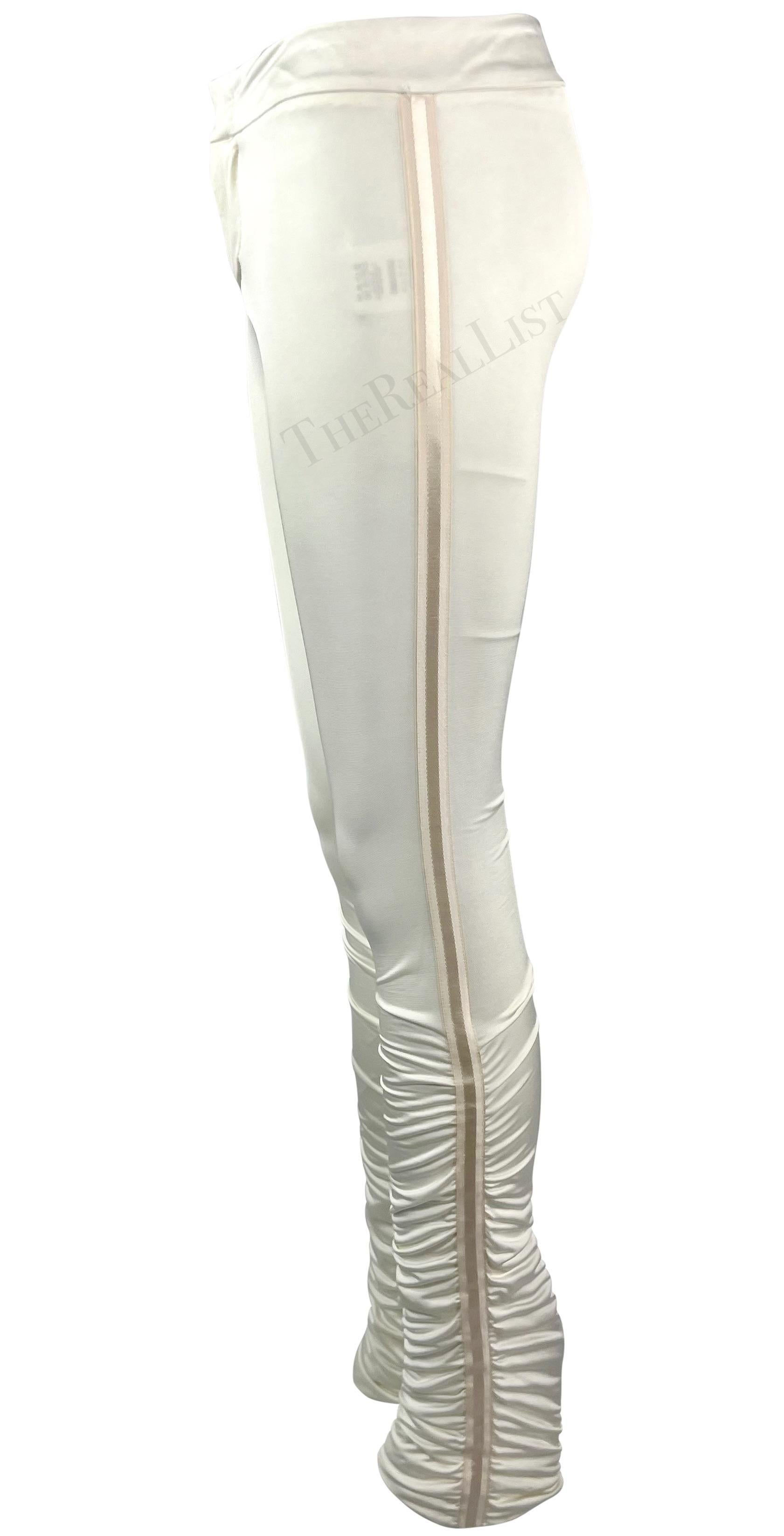 Whiting présente un pantalon blanc Gucci, dessiné par Tom Ford. Issu de la collection automne/hiver 2004, ce pantalon en satin ajusté présente des fronces aux mollets et est complété par un ruban rayé monochrome de chaque côté. Jamais porté, ce
