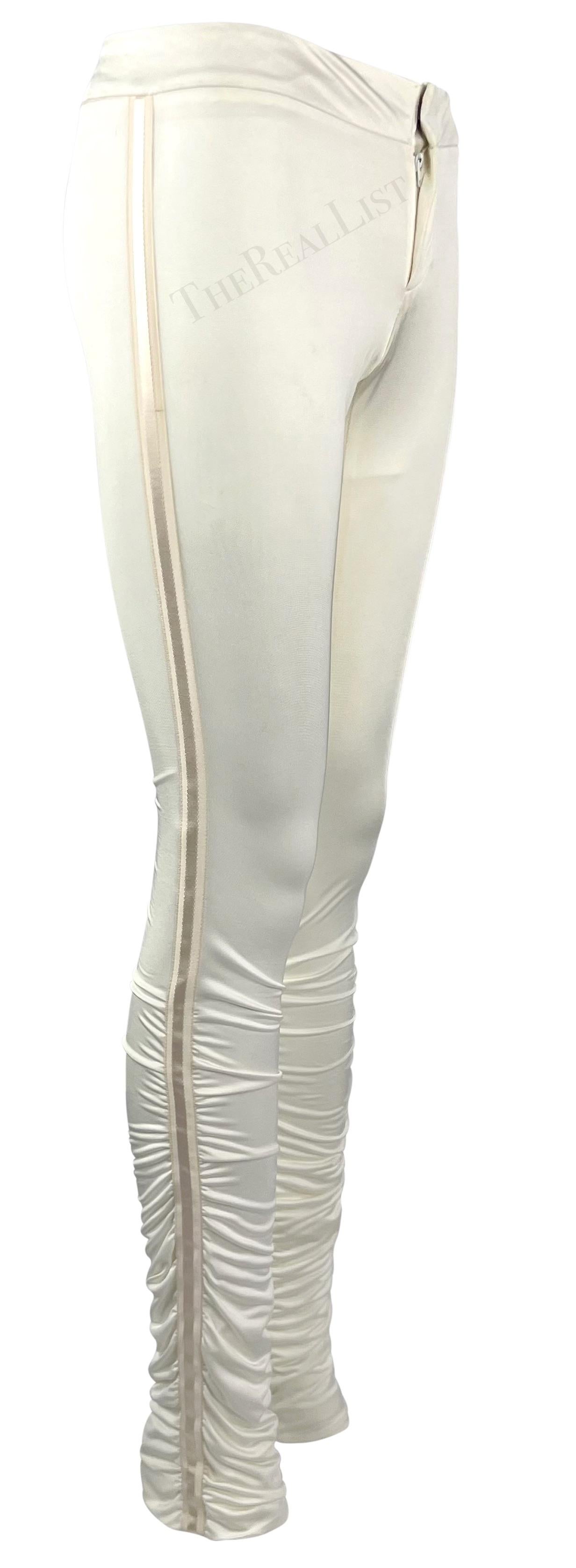 Ich präsentiere eine weiße Gucci-Hose, entworfen von Tom Ford. Diese figurbetonte Satinhose aus der Herbst/Winter-Kollektion 2004 ist an den Waden gerafft und wird durch ein einfarbig gestreiftes Band an beiden Seiten vervollständigt. Diese