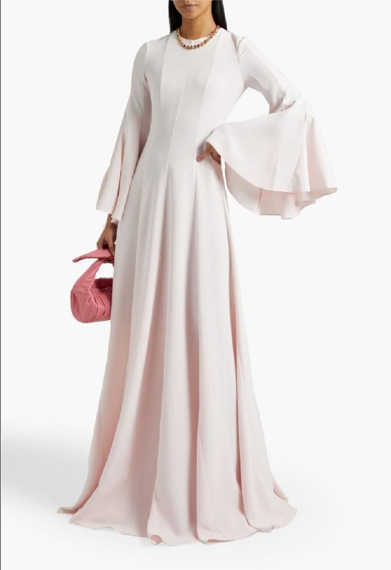 Romántico y elegante, este vestido de Oscar De La Renta está confeccionado en crepé de seda fluido en un suave tono rosa pastel. La silueta presenta un elegante diseño hasta el suelo, con un corpiño ajustado y sutiles costuras princesa que acentúan