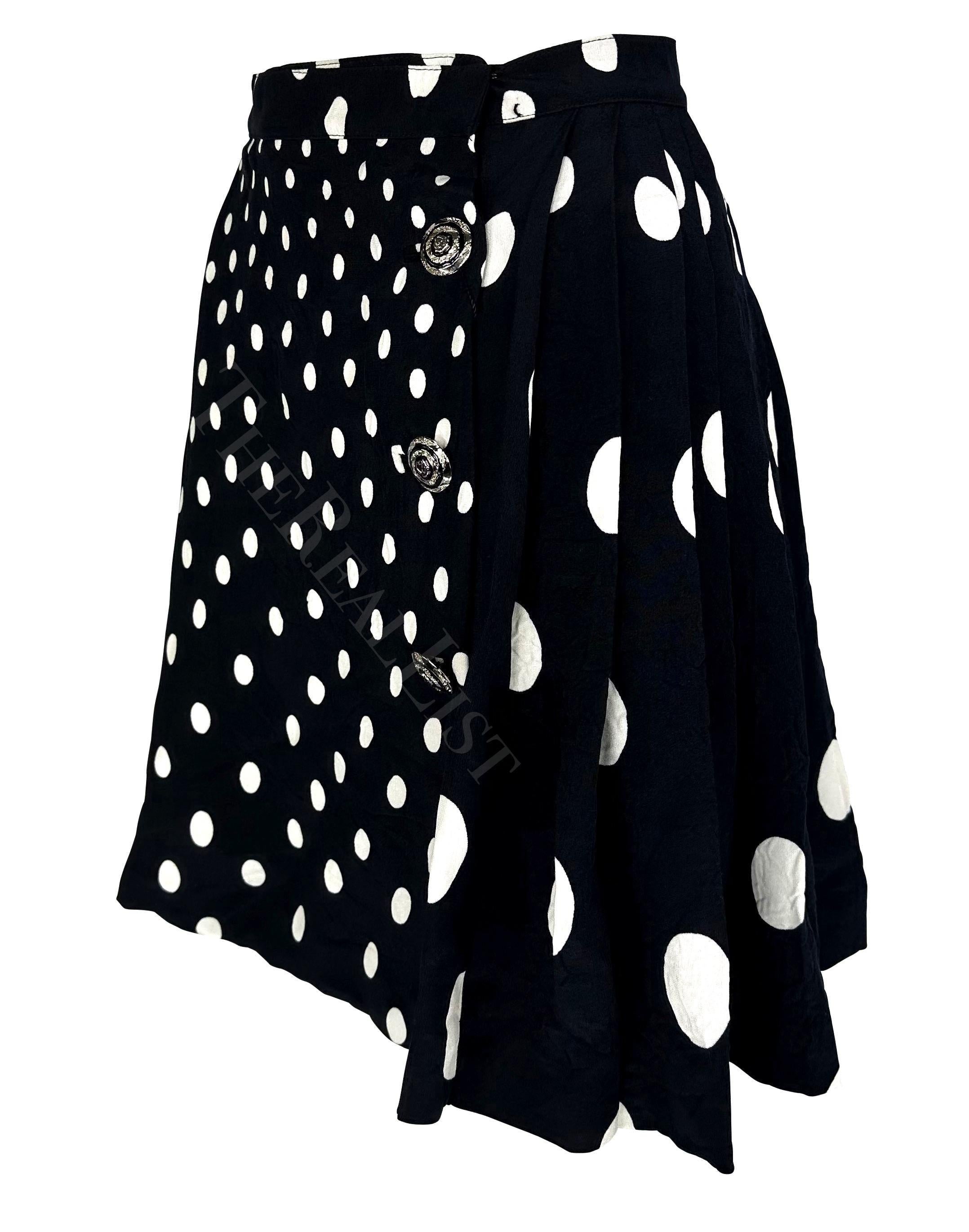Ti presentiamo una favolosa gonna a pieghe a pois bianchi e neri firmata Gianni Versace. Dalla collezione Primavera/Estate 1994, questa gonna volutamente stropicciata è ricoperta di piccoli e grandi pois ed è completata da chiusure con bottoni