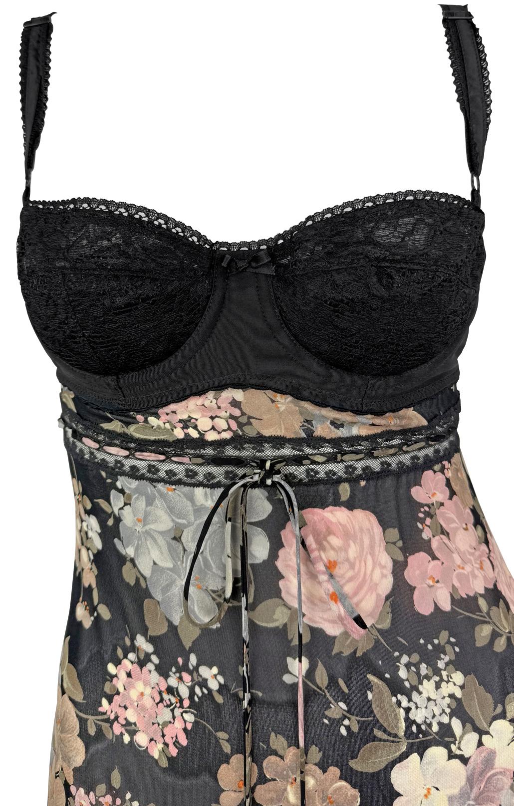 From Dolce & Gabbana’s Spring/Summer 1997 collection, this slip dress features a delicate neutral floral print on sheer black stretch fabric. The design is anchored by a structured black bustier with underwire cups and adjustable lingerie-style
