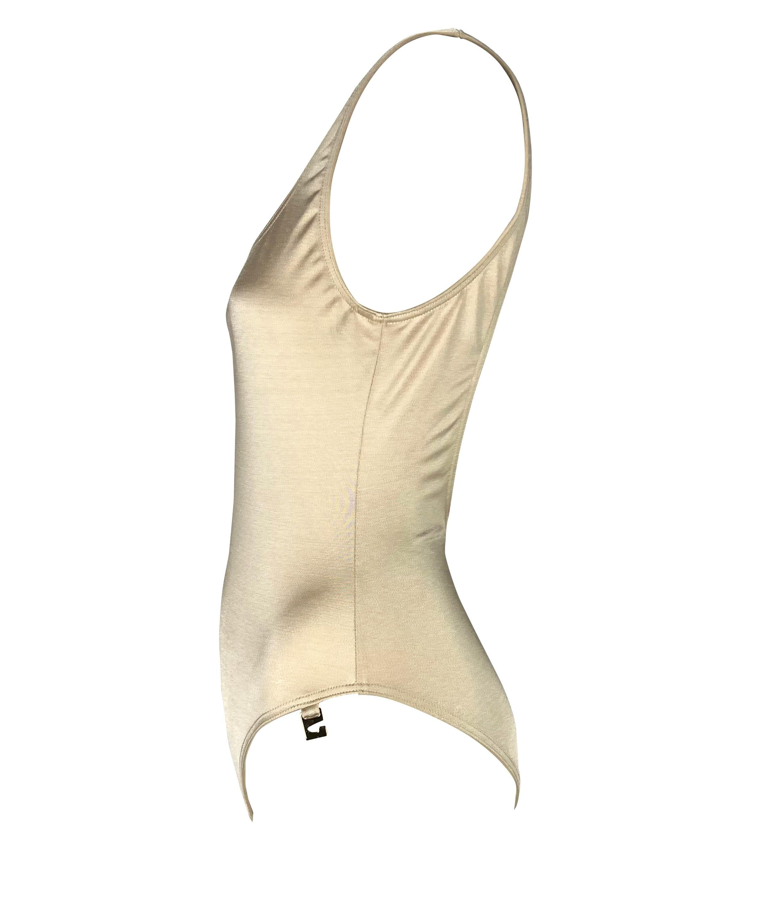 Presenting a gorgeous beige Gucci one-piece swimsuit, designed by Tom Ford. From the Spring/Summer 1997 collection, this bathing suit features a scoop neckline, open back, and gold-tone abstract Gucci 'G' medallion. Never worn before, this