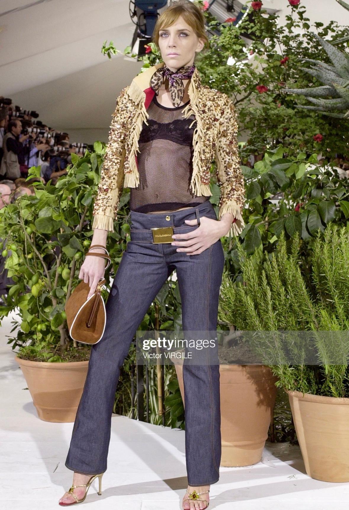 Presenting a fabulous pair of deep navy Dolce & Gabbana jeans. From the Spring/Summer 2001 collection, these jeans debuted on the season's runway as part of look 18, modeled by Hannelore Knuts. These pants stand out with a large gold-tone 'Dolce &