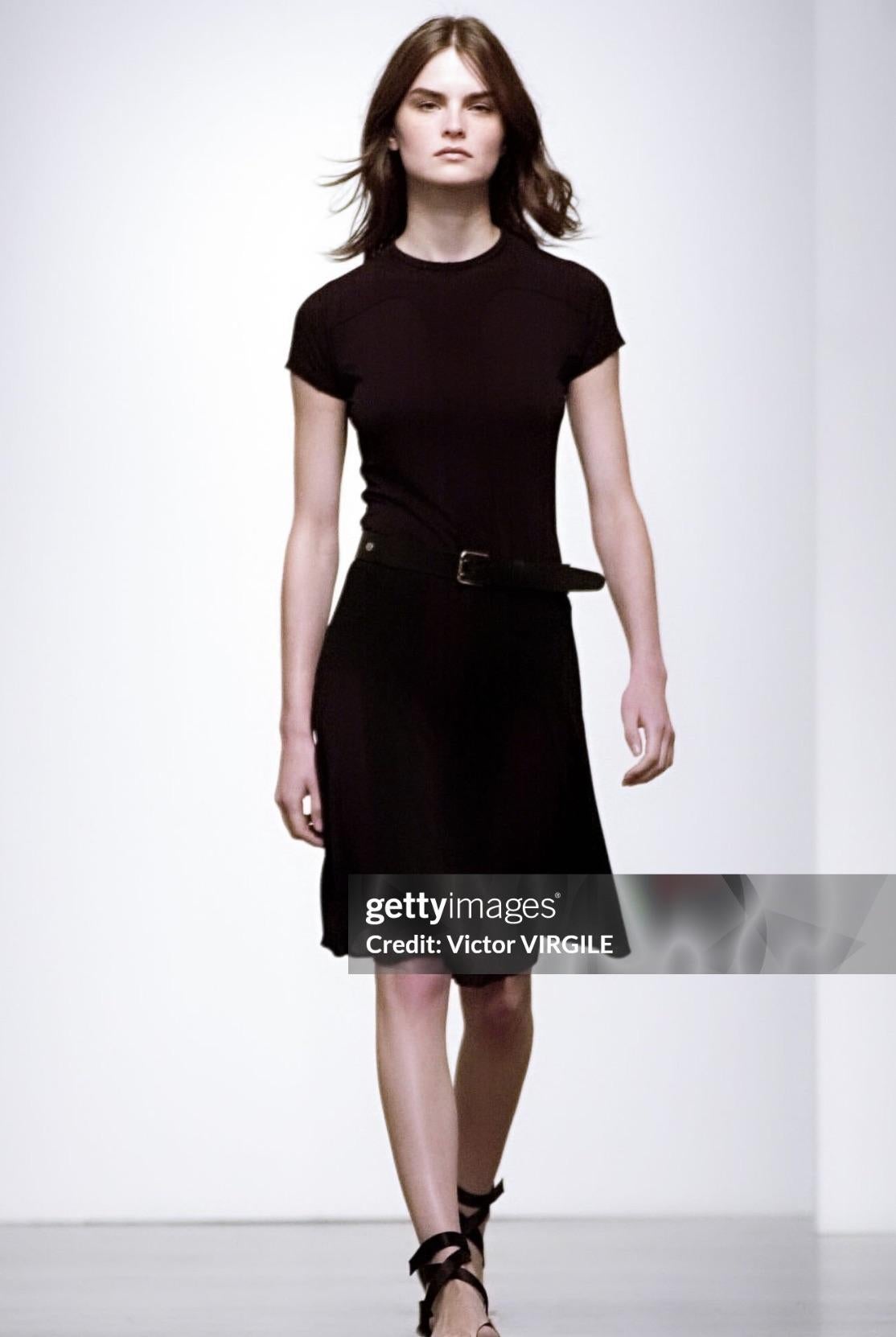  De la pasarela Primavera/Verano 2002 de Calvin Klein Collection, este vestido midi negro transparente presenta una silueta ceñida al cuerpo con paneles estructurados. El diseño incluye mangas cortas, escote redondo y dobladillo acampanado para un