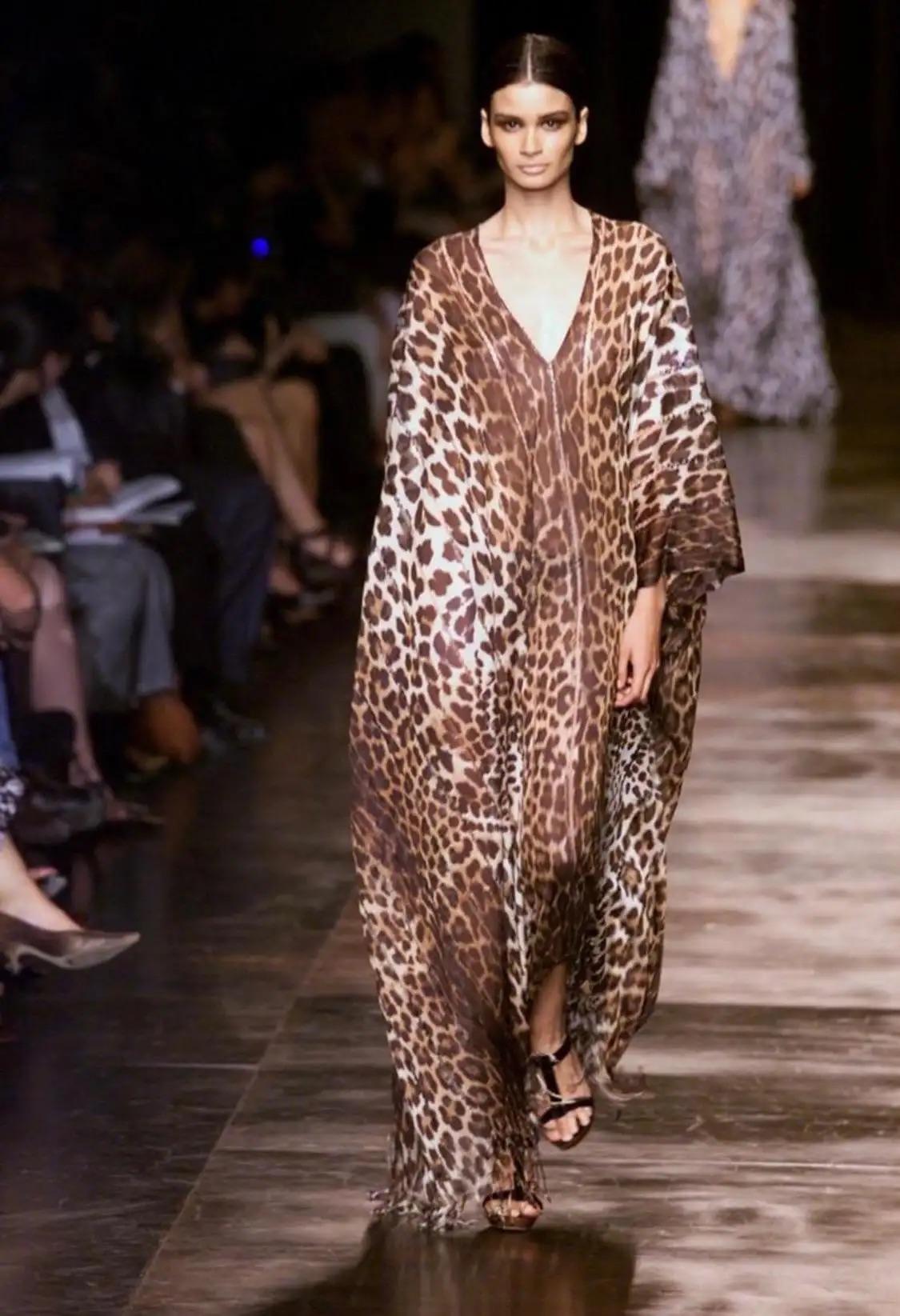 Voici une robe à imprimé léopard de la collection Yves Saint Laurent Rive Gauche, créée par Tom Ford pour la saison printemps/été 2002. Cette robe présente un décolleté plongeant, un dos ouvert et une traîne impressionnante. L'abondance de tissu est