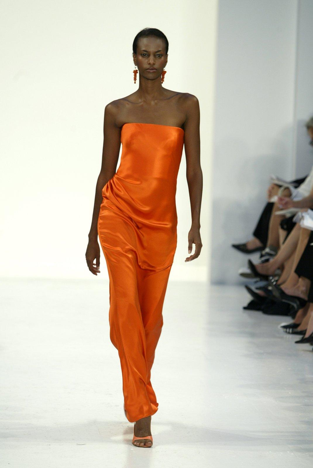 From Ralph Lauren’s Spring/Summer 2004 collection, this unworn sleeveless mini dress is crafted from vibrant orange silk satin and cut with a flared silhouette. Designed with a high halter neckline and delicate crisscross straps at the open back,