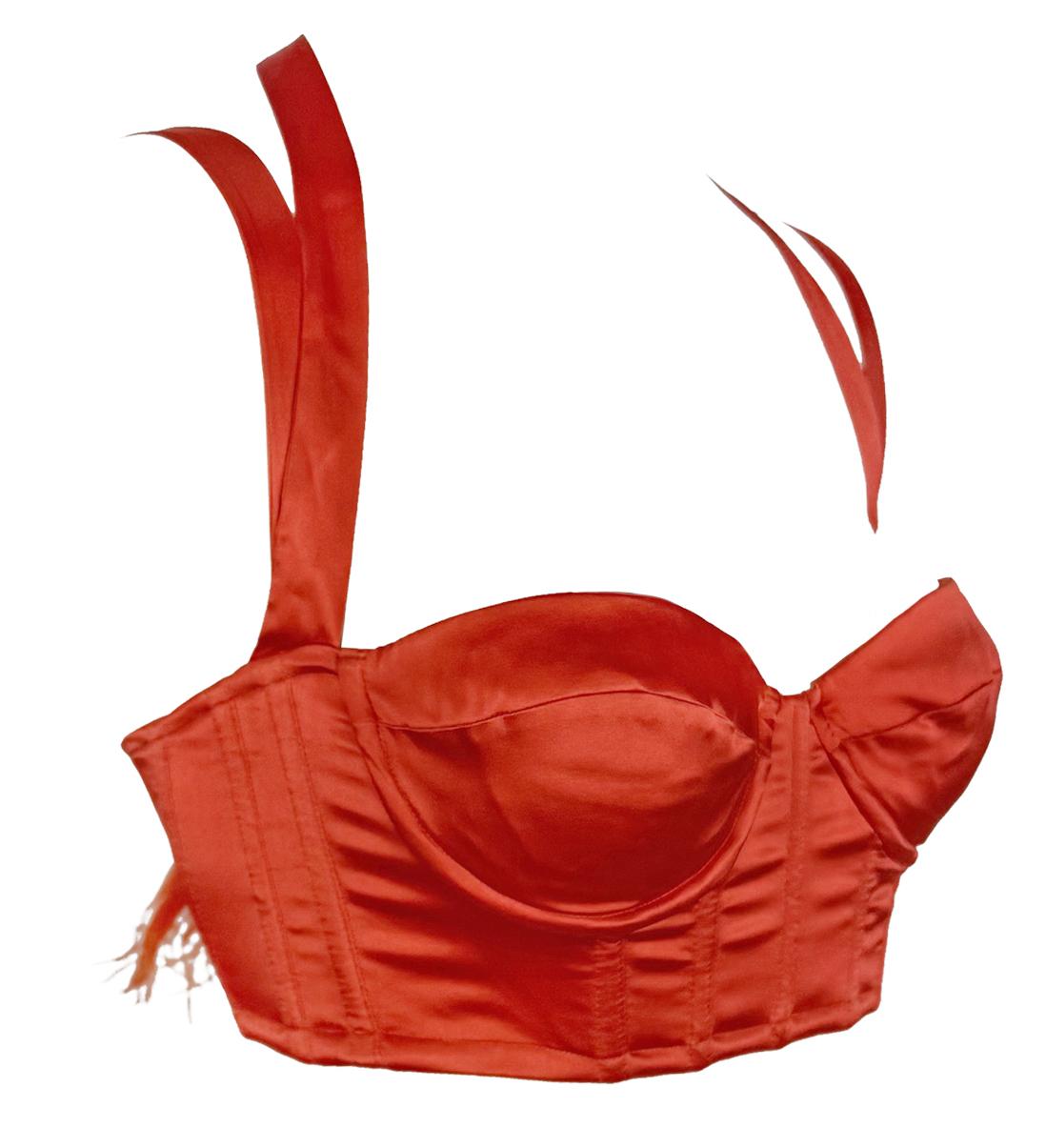 From Roberto Cavalli’s Spring/Summer 2004 collection, this new-with-tags corset-style crop top is crafted from a vibrant red-orange satin. It features molded cups, boning throughout, and dramatic ribbon ties at the shoulders and back, finished with
