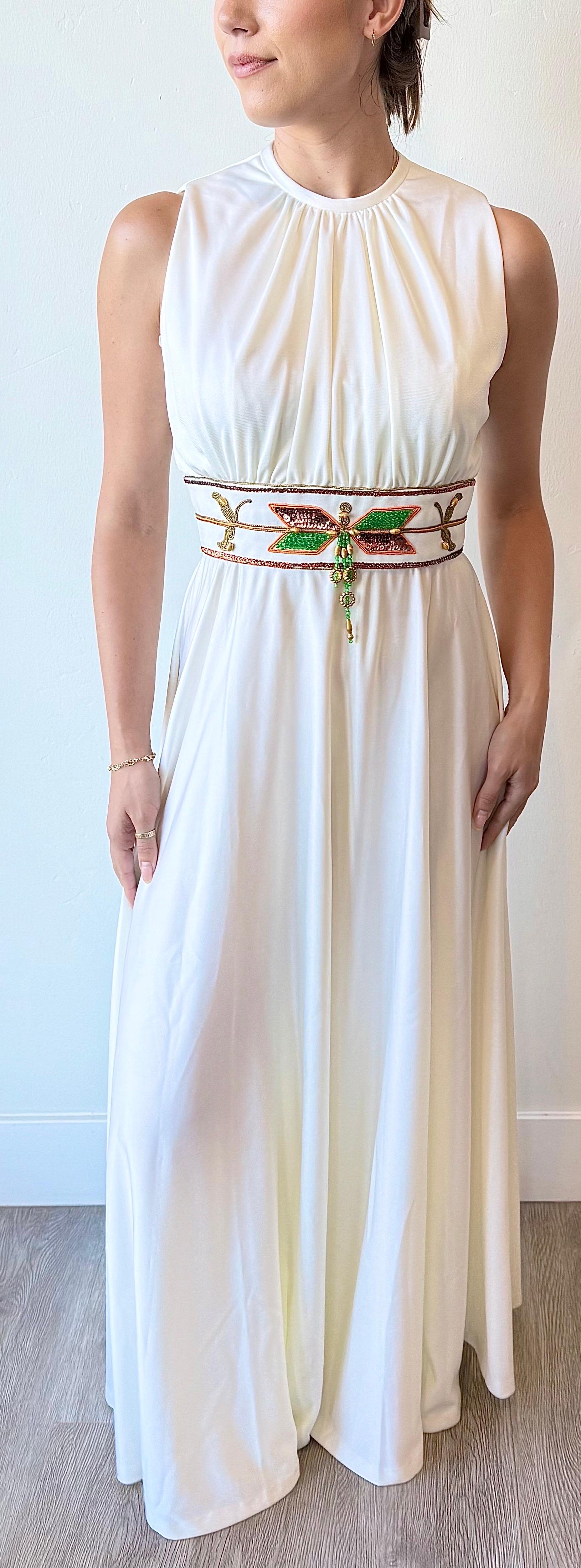 Elegante maxivestido blanco vintage de los años 70 de Birdine's Sunshine Fashions que muestra una silueta griega fluida con escote suavemente fruncido, corpiño sin mangas y espalda abierta en forma de ojo de cerradura. Destaca el panel de la cintura