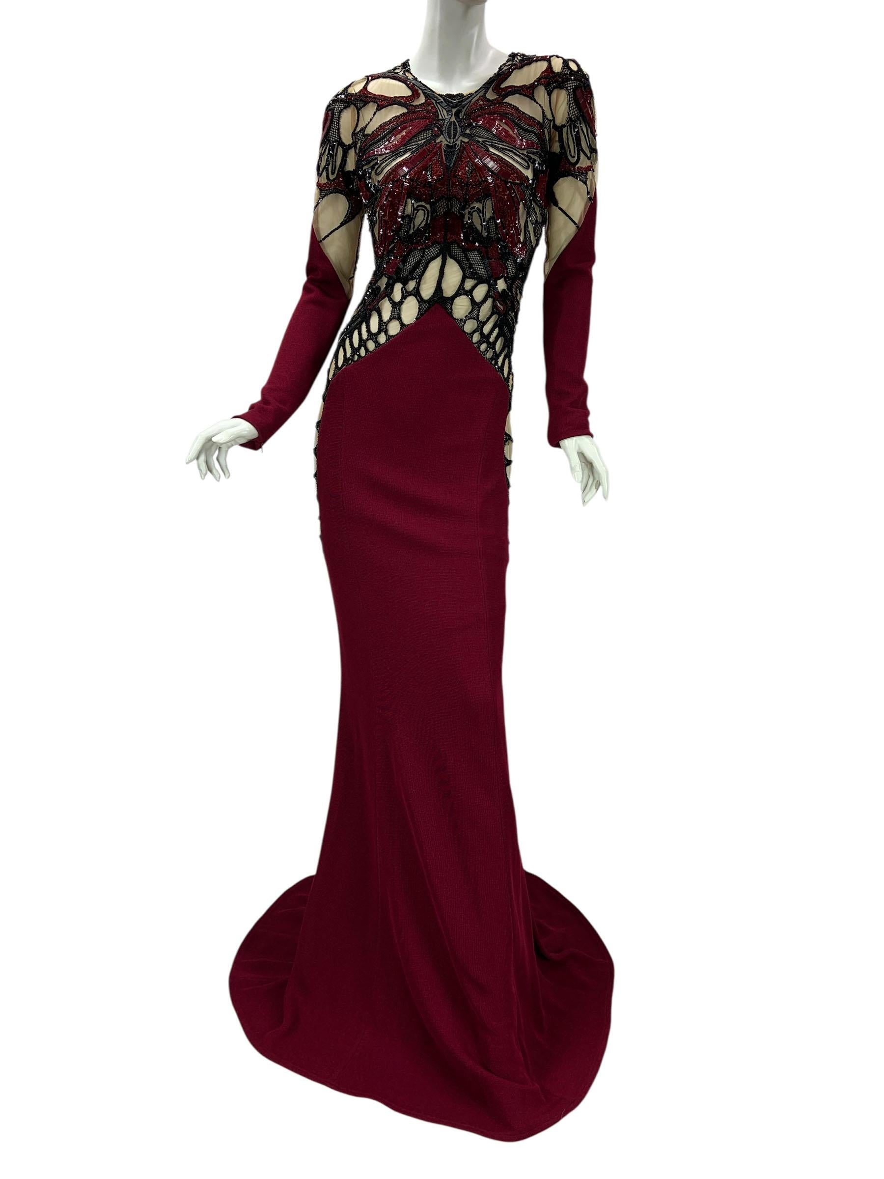 Exquisite Zuhair Murad floor-length gown crafted in a rich burgundy stretch fabric, featuring intricate illusion paneling and elaborate embroidery. The bodice and sleeves are adorned with black and deep red beadwork, sequins, and appliqué in an