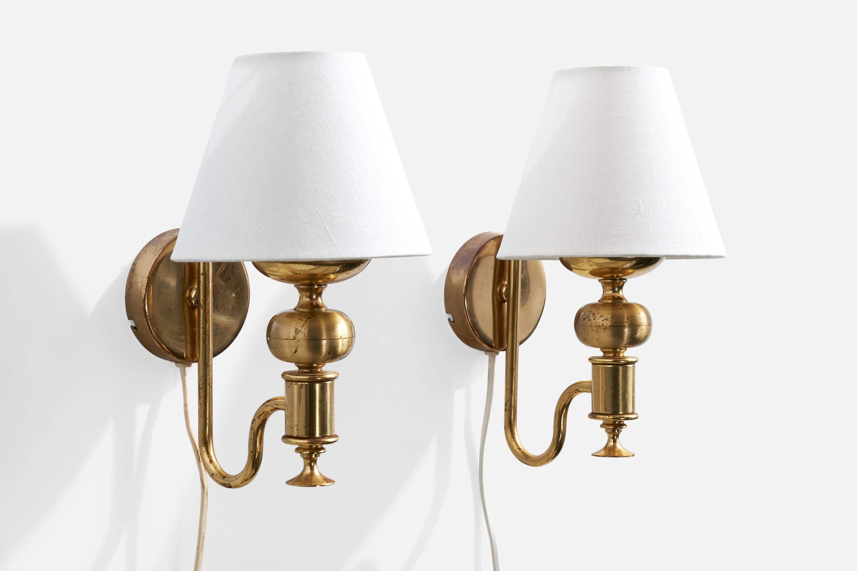 A pair of brass and white fabric wall lights produced by Nya Öia, Sweden, c. 1970s.

Overall Dimensions (inches):  11” H x  6.125” W x  7.625“ D

Back Plate Dimensions (Inches):  3.25” H x 3.25” W x .875” D

Bulb Specifications: E-14

Number of