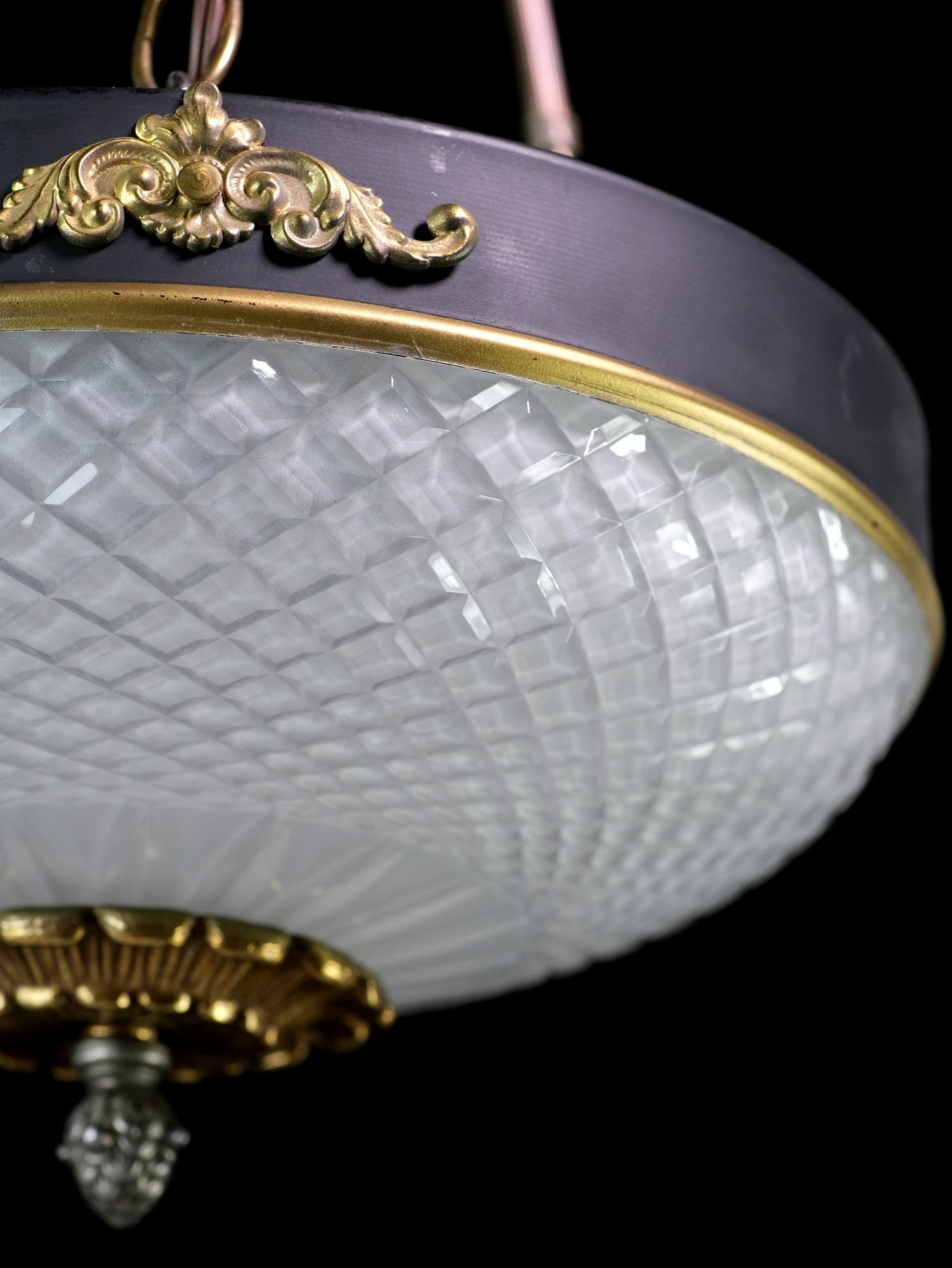 This pair of empire style pendant dish lights are original to the NYC Waldorf Astoria. They feature frosted cut glass with etched details with a decorative rim suspended by three brass rods attached to the brass canopy. These lights graced the