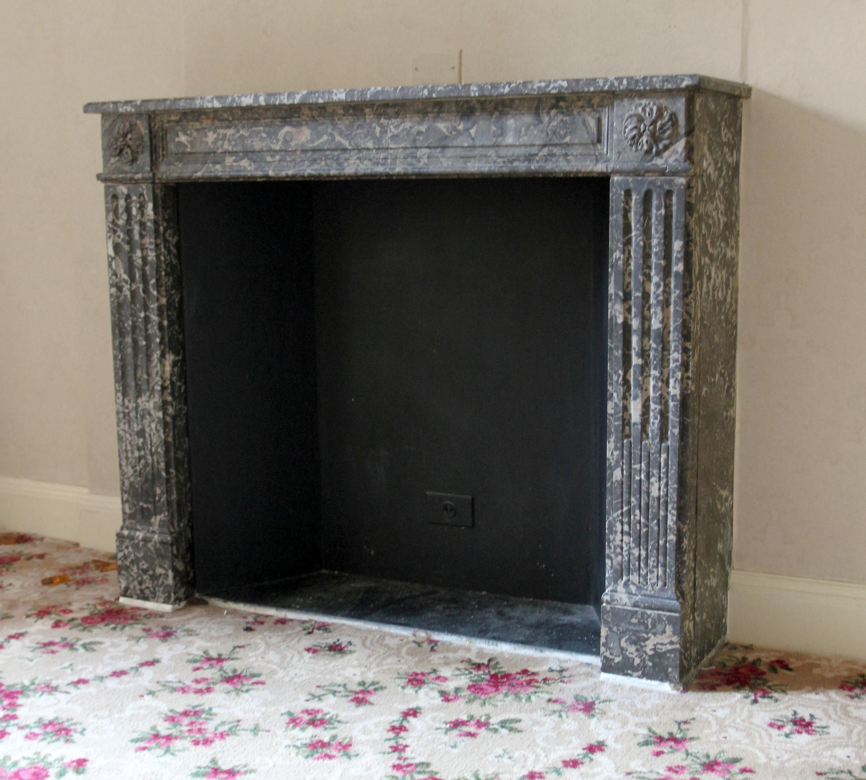 Early 20th century hand carved marble mantel made from gray and white veined marble. Each side features a fluted design and floral top corners. This mantel was brought over from France and installed in the then newly built Waldorf Astoria Hotel