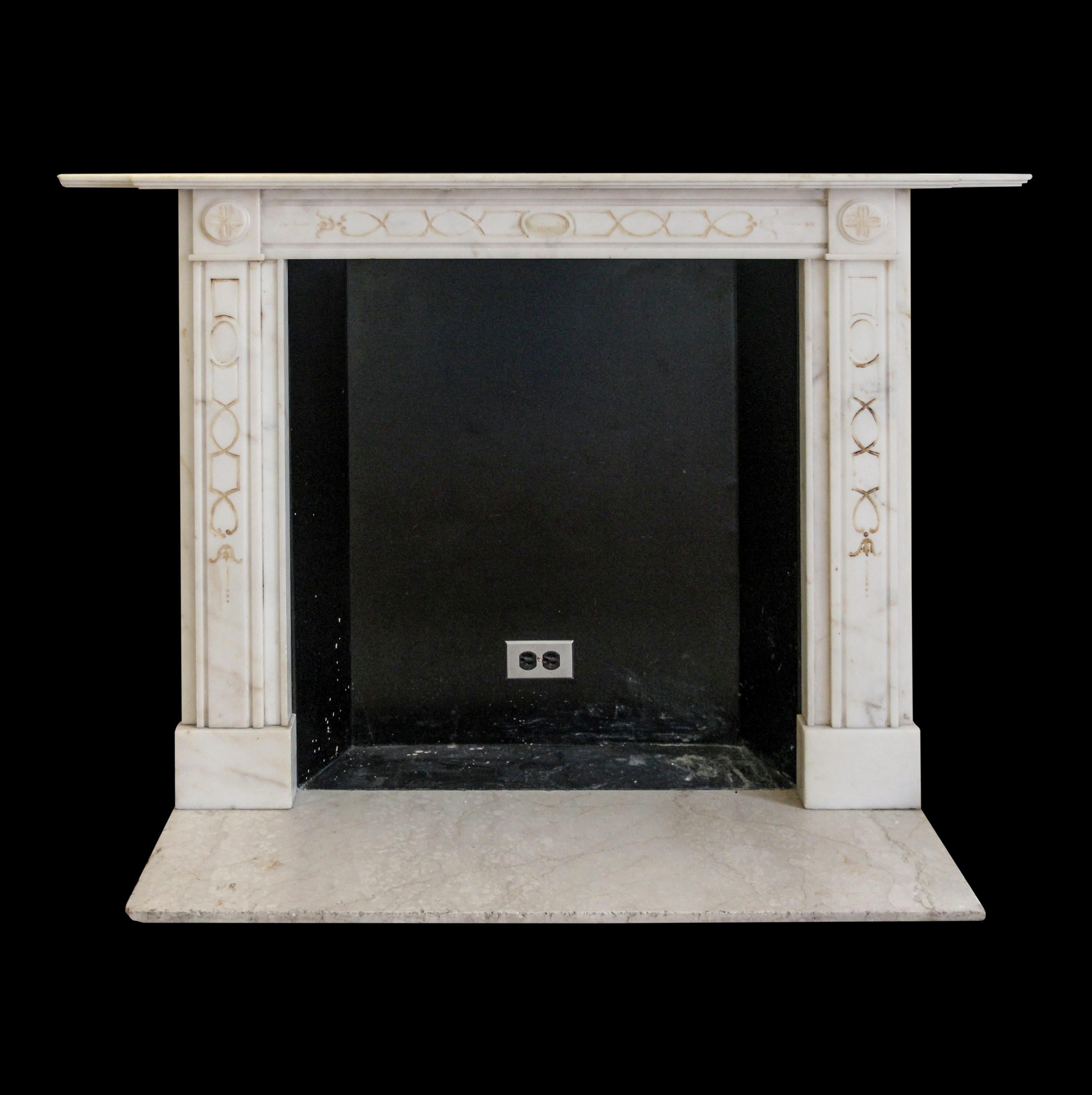 Early 20th Century English Regency style hand carved marble mantel featuring very simple carved line detailing across the front apron and corners also along both vertical legs. The gold coloring within these carved lines has somewhat faded. The