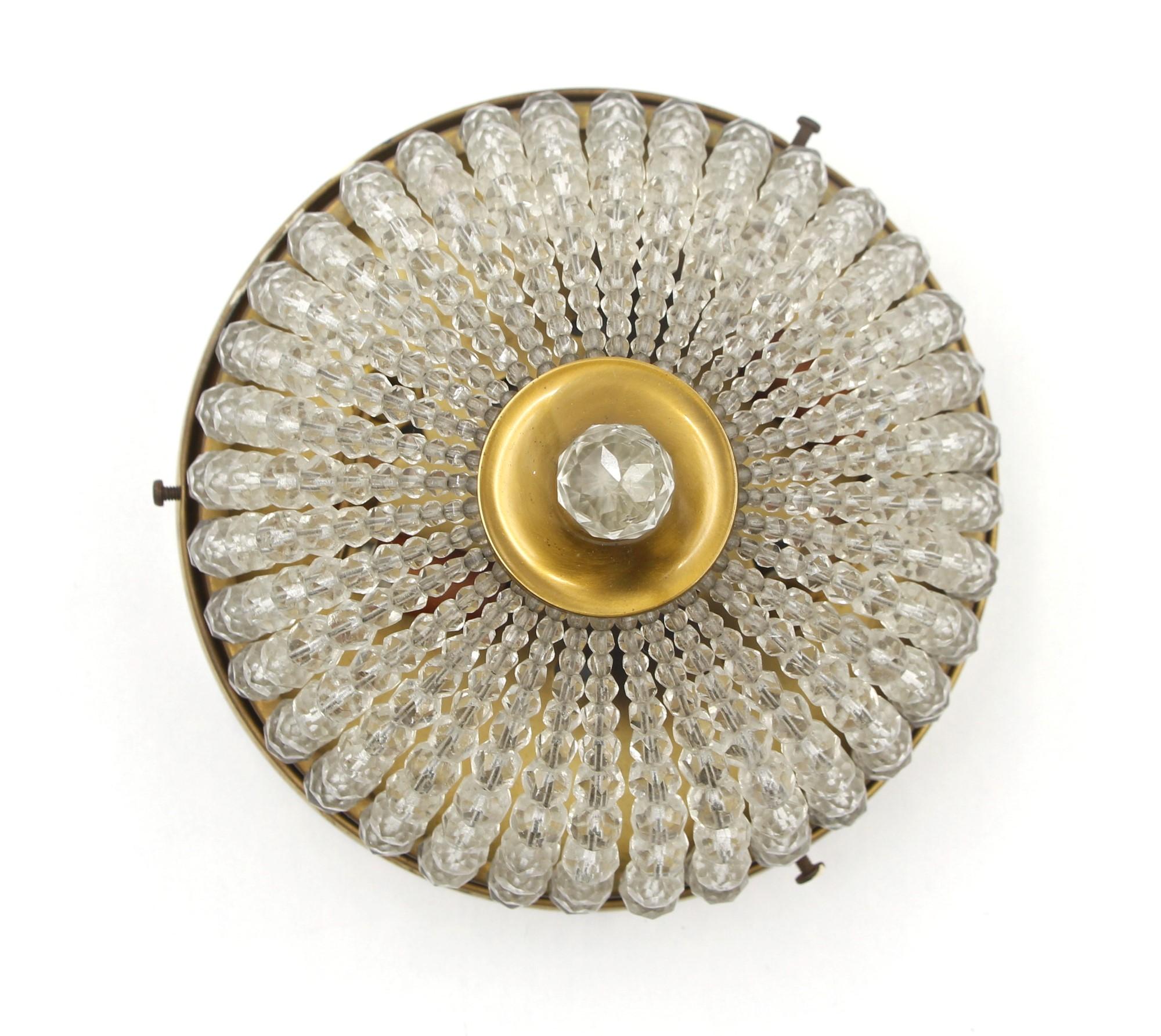 This 1920's beaded crystal flush mount light is an original to the suites of the Waldorf Astoria Towers in New York City. The beads are connected to the polished brass frame and have a faceted crystal finial at the bottom. The price includes
