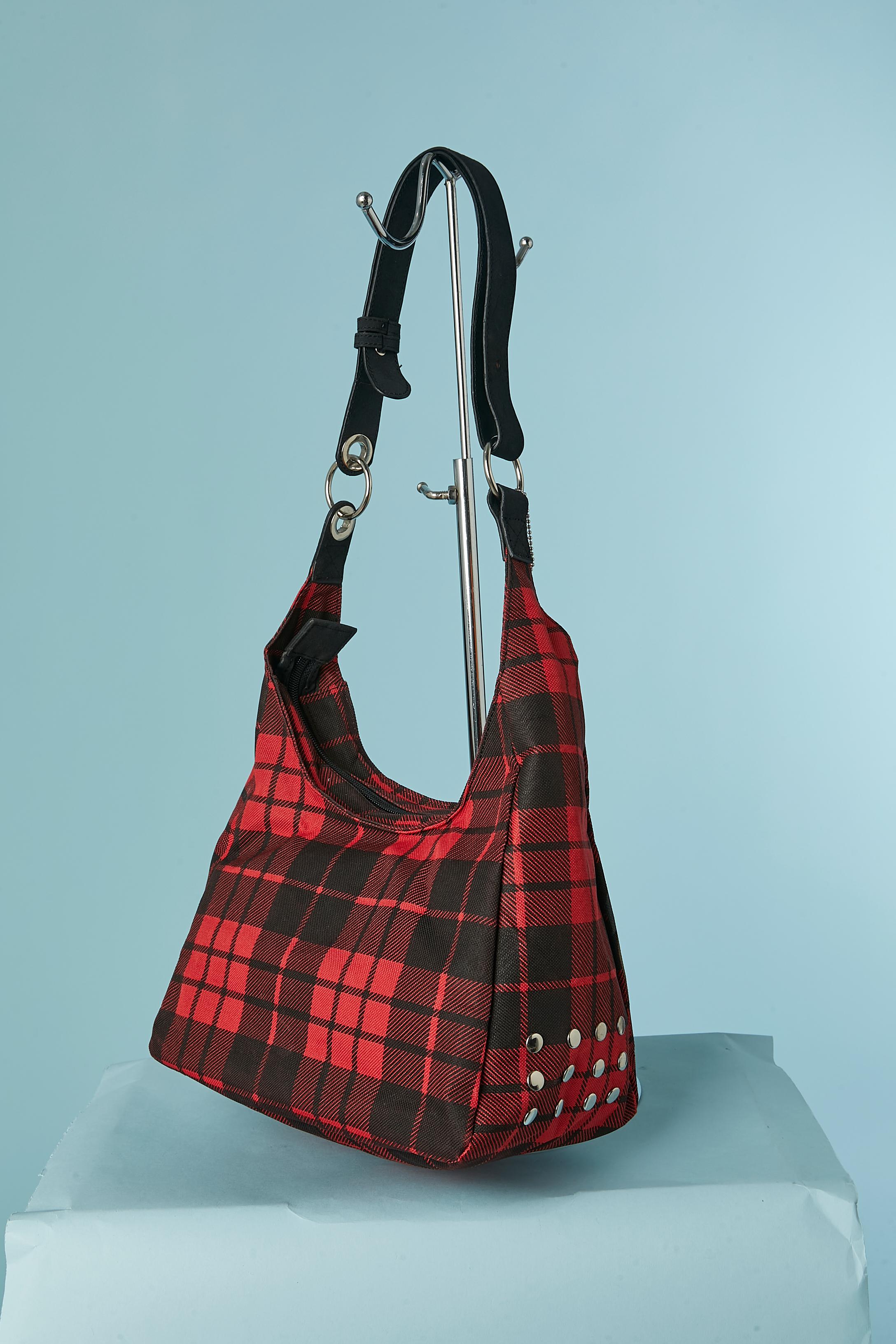 Nylon Tartan shoulder bag with JCDC face print on. Orange nylon lining. 
Zip closure on the top. One transparent small pocket outside + 3 inside pockets ( 2 flat and one with zip closure. 
Adjustable shoulder strap.
SIZE : 25cm X 35cm X