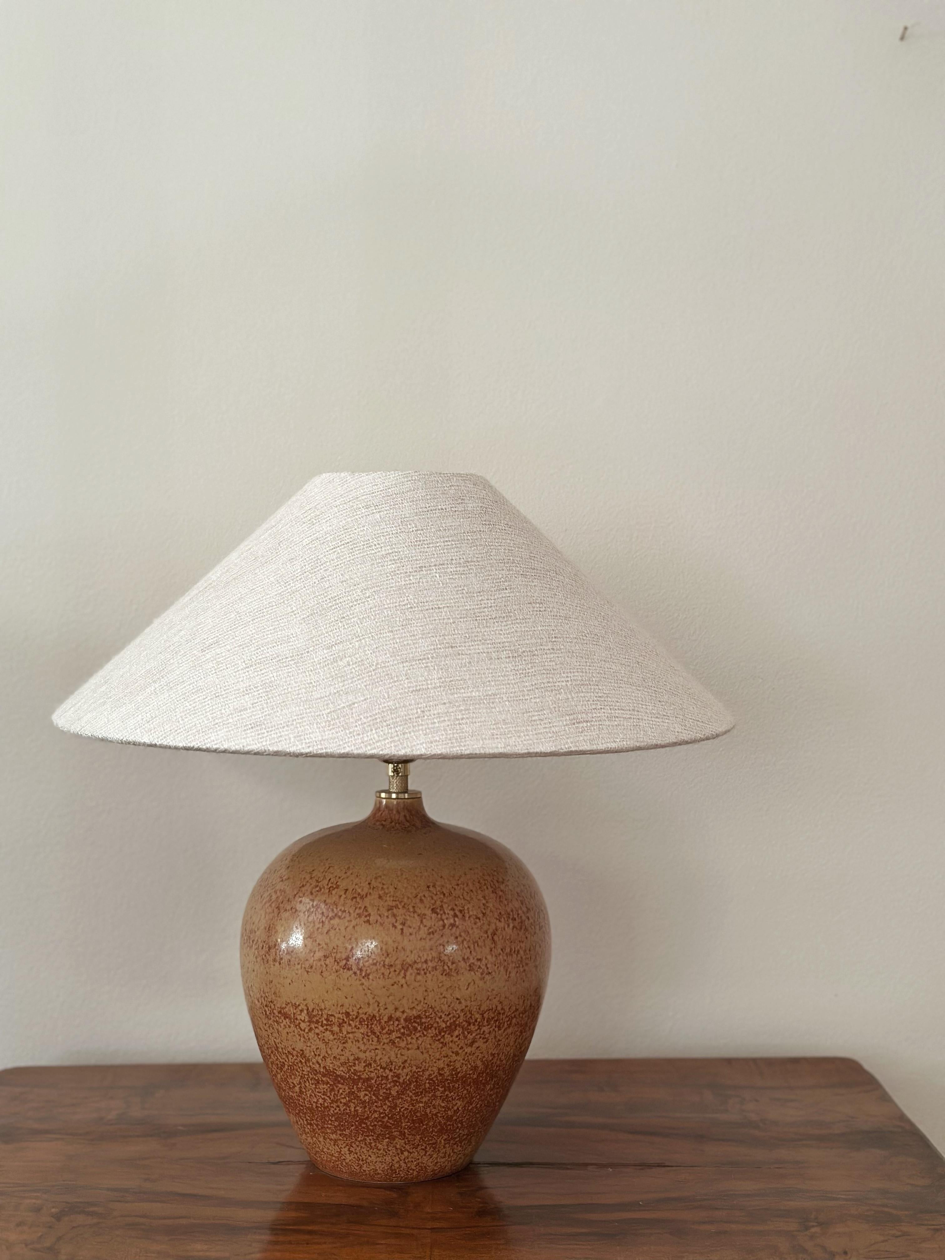 Rare et unique lampe de table en grès fabriquée à la main par le céramiste et designer suédois Gunnar Nylund pour Rörstrand, Suède. 1940's. 
Le corps fait preuve de simplicité et la glaçure passe du brun clair à un brun plus profond en s'estompant.