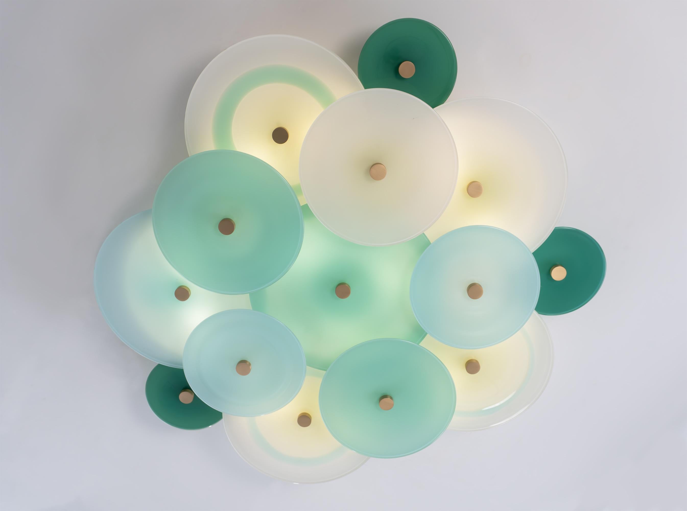 The Nymphaea Chandelier is a flexible and customizable arrangement of handblown glass discs in a layered myriad of translucent colors with delicate brass hardware. The Nymphaea Collection evokes the delicate dance of colorful blossoms amid the