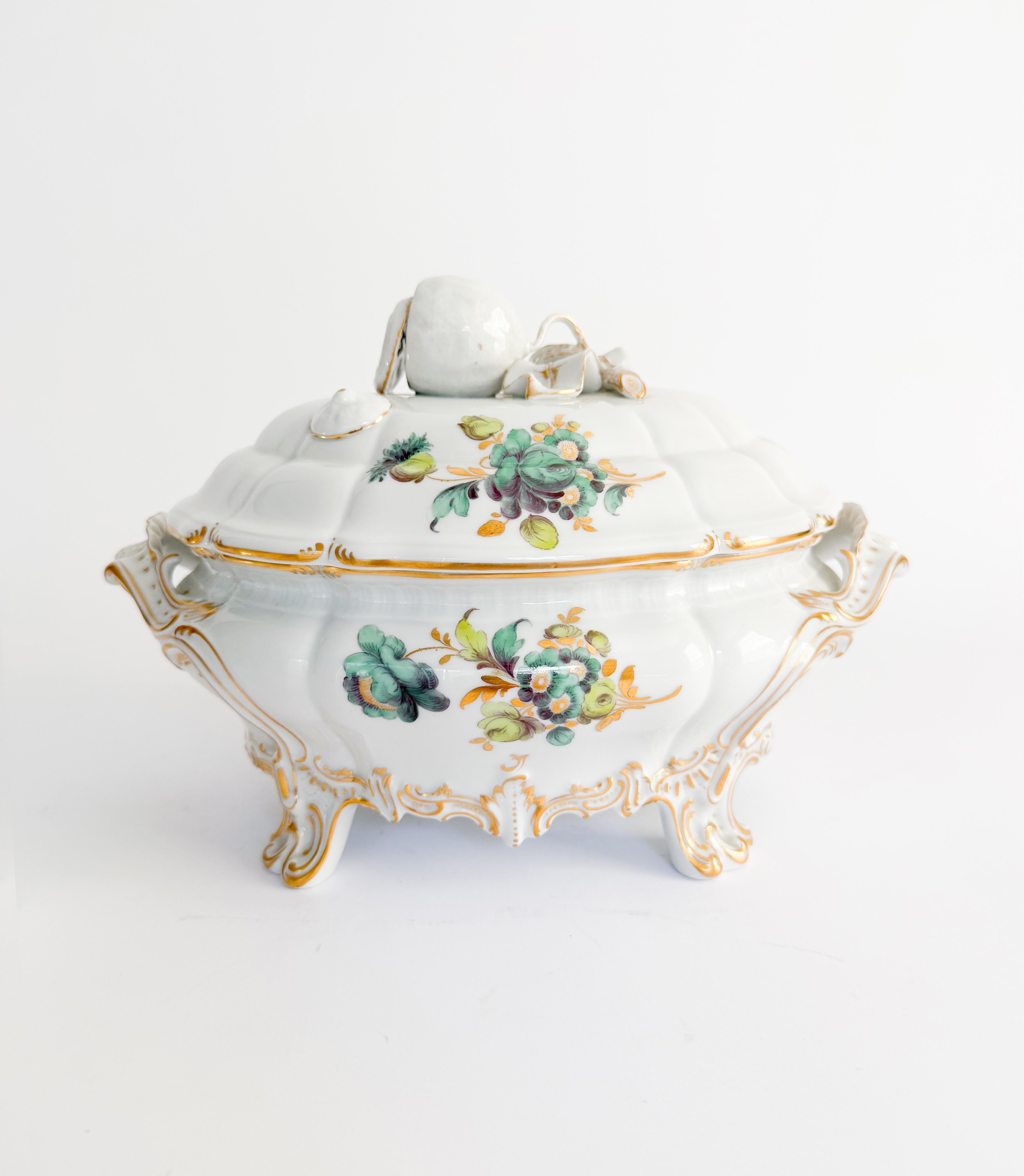 Cette étonnante soupière rococo en porcelaine peinte à la main par Nymphenburg présente un bord doré, un motif floral bleu et vert et un joli fleuron de couvercle en forme de citron. Décorations dorées le long du bord, des poignées et des pieds.

Le