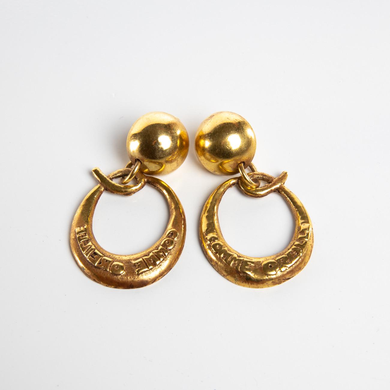 This pair of clip-on earrings is made of gilded bronze balls on which are suspended a large letter 