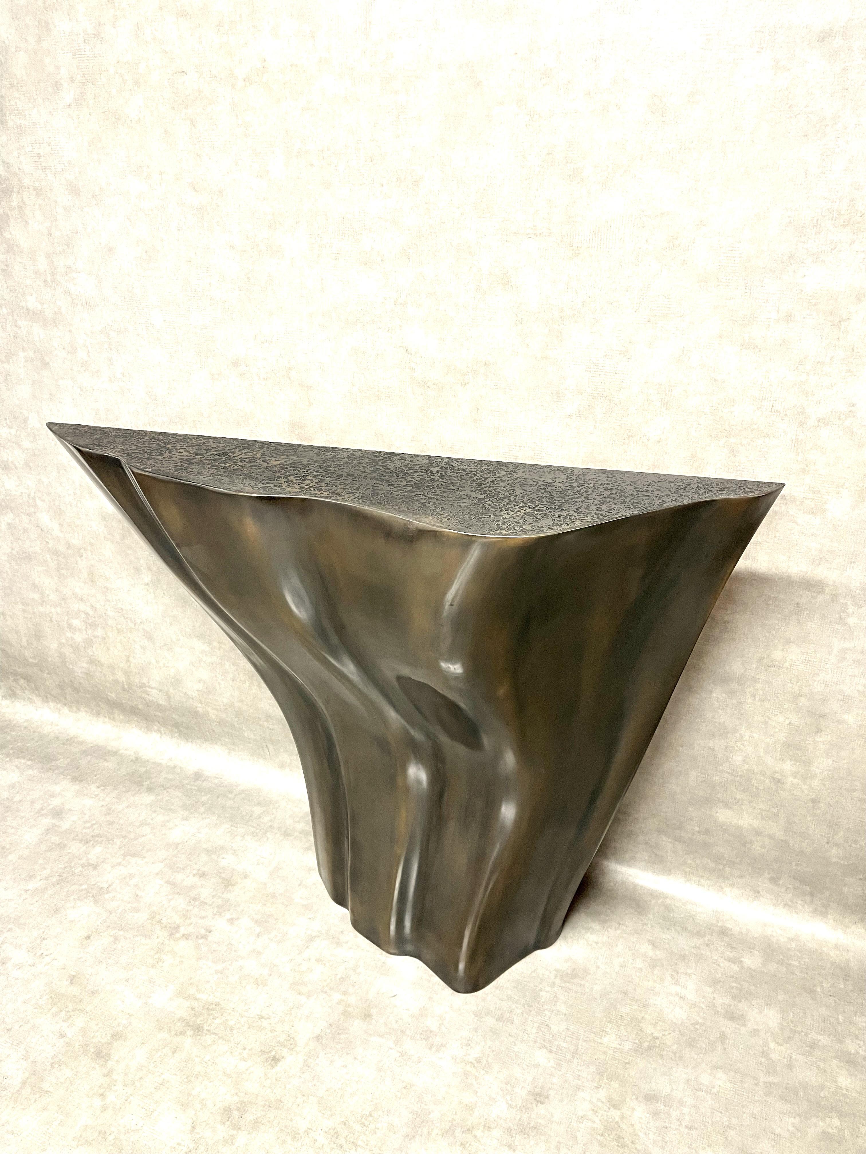 The O2 console table is carved in oak which is sheathed with (patinated and waxed) bronze. The (patinated and waxed) bronze table top is sculpted with organic shapes. The console can be wall-mounted.  The bracket is located on the back of the