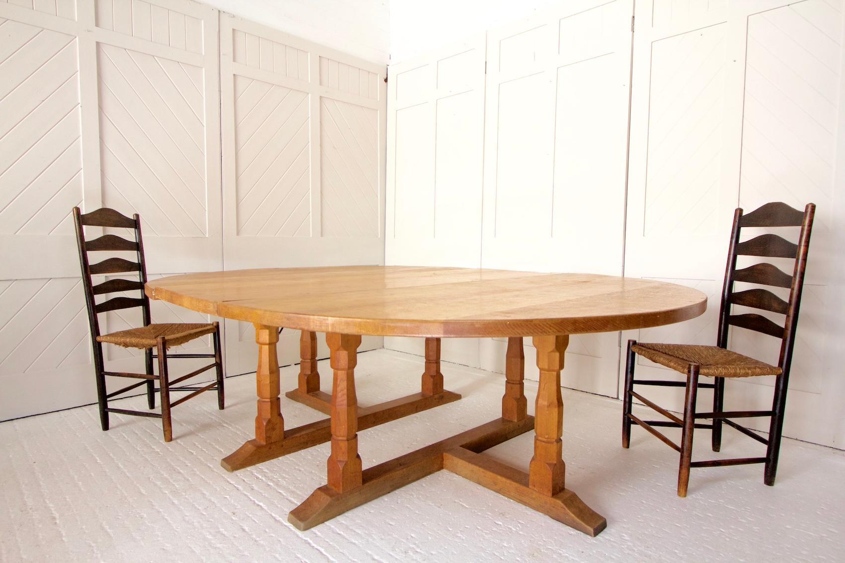 An azed oak circular extending dining table with 6 legs and a separate extension leaf to seat up to 12 people.

This table was designed by Wilf Hutchinson and his signature ‘squirrel’ has been carved on the leg. Hutchinson trained under Robert