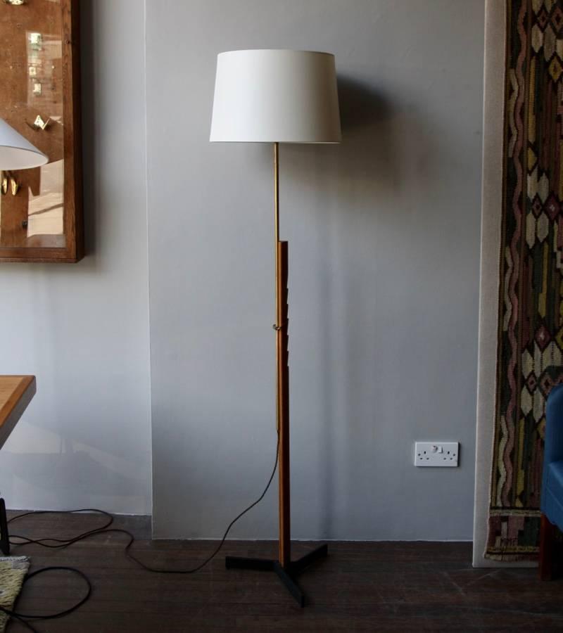 Floor light in polished brass and oak by Svend Aage Holm Sørensen, Denmark, 1950s. 
The upper part of the stem in solid brass, fits onto the lower - made out of oak - through a brass hook that can hang on six carved grooves. The lamp is thus