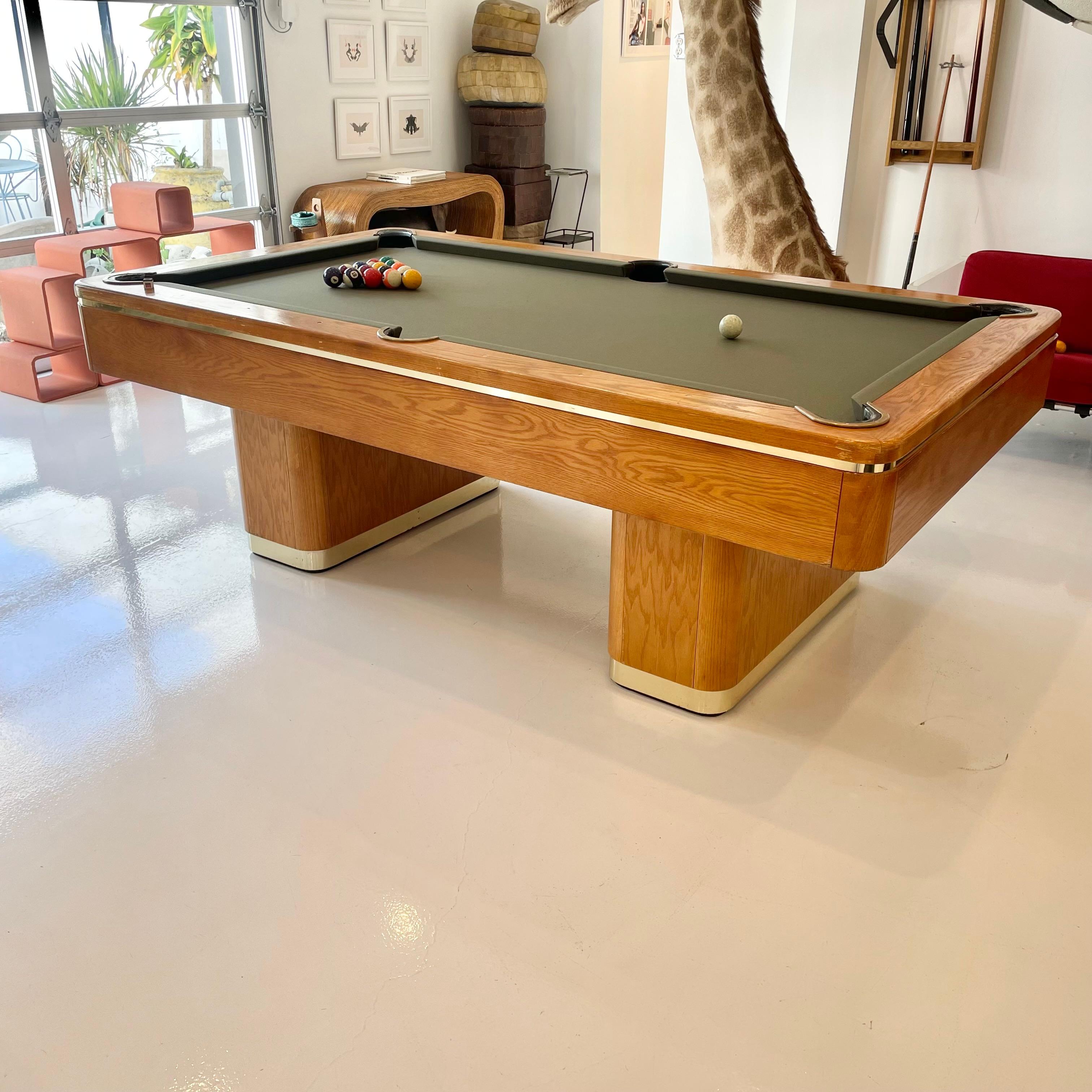 Elegant oak and brass pool table by Golden West custom made in USA, 1980s. Solid oak. Leather pockets with brass screw in clasps around the mouth of each pocket. Beautiful dual pedestal design give this table a modern look while the oak gives it a