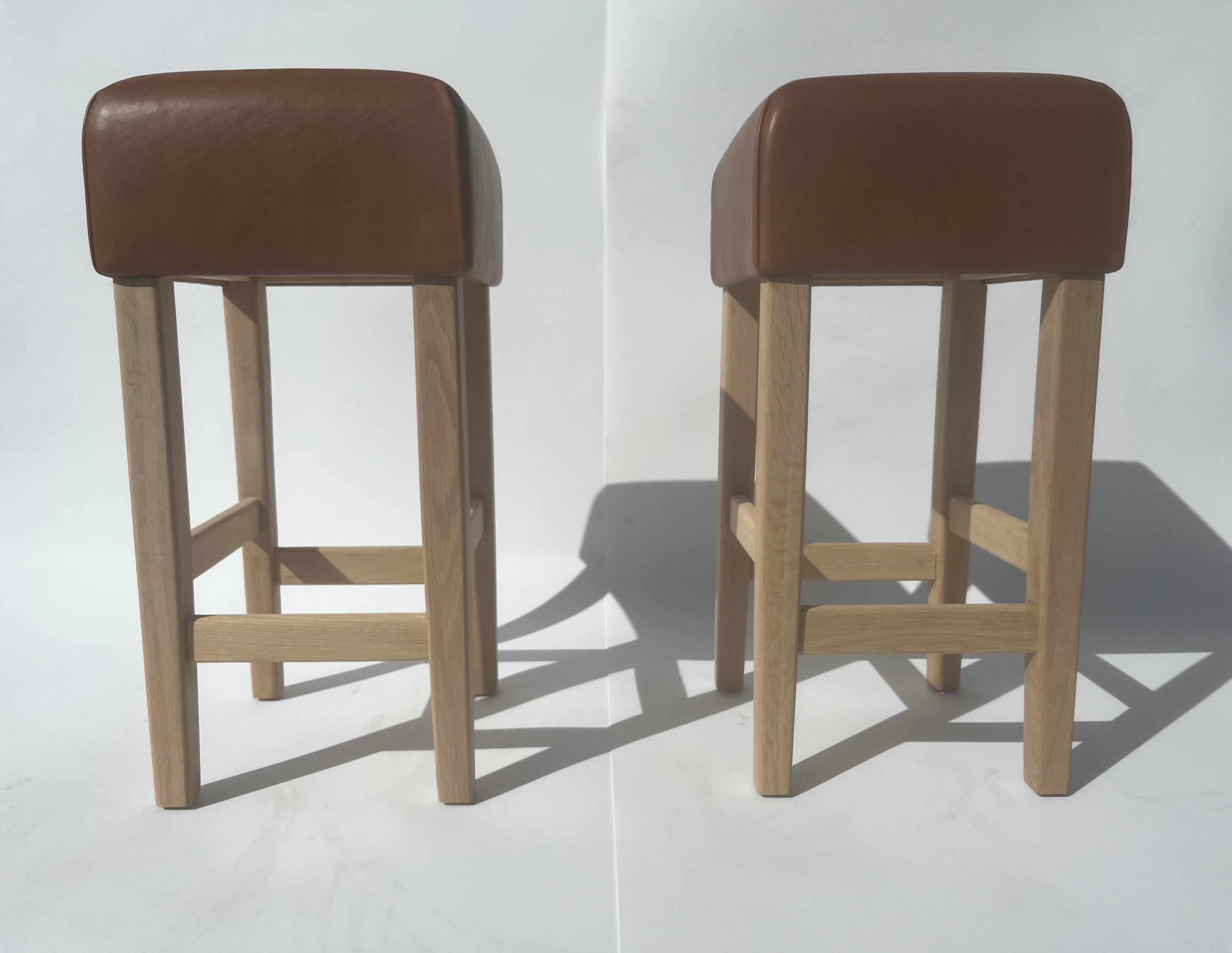Magnifiques tabourets de bar dans le style de Jean-Michel Frank, base en chêne blanc avec assise en cuir cognac. Le cuir est très épais et la base en chêne blanc est faite pour durer éternellement. Le cuir a une belle patine. La base en chêne blanc