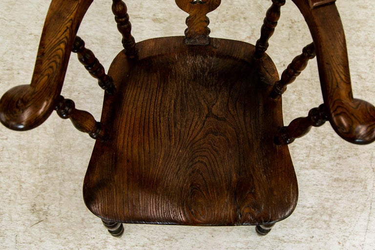 The back of this English chair is supported by a pierced splat and eight turned spindles. The scrolled arms are supported by six shaped turned spindles and a small pierced slat. The turned, shaped legs are joined by a turned 
