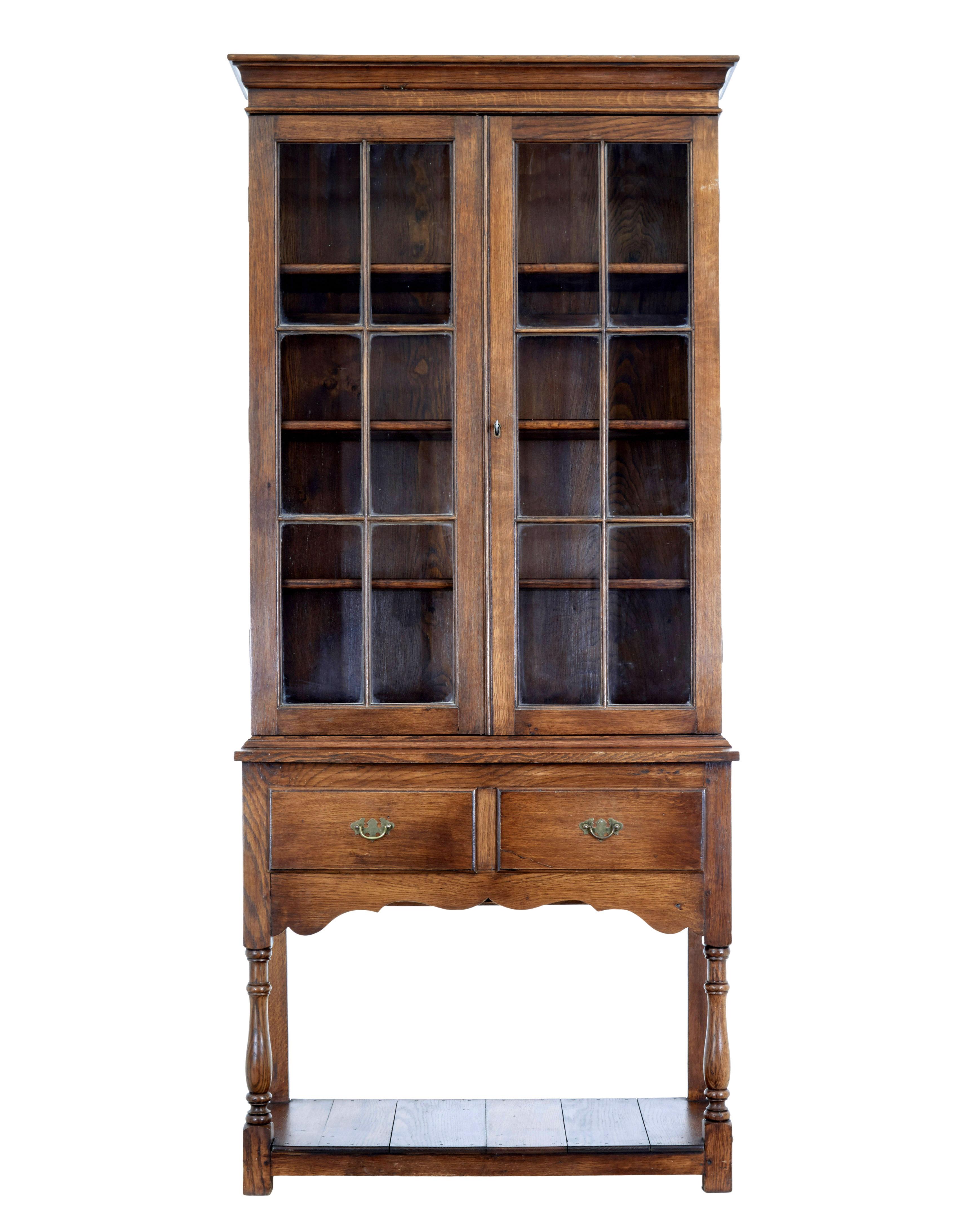 Oak and glazed cabinet on base circa 1980.

Good quality 1 off piece of furniture, comprising of 2 sections.

Top section with cornice, below which are a pair of glazed double doors that open to reveal a interior of 3 shelves. Bottom section