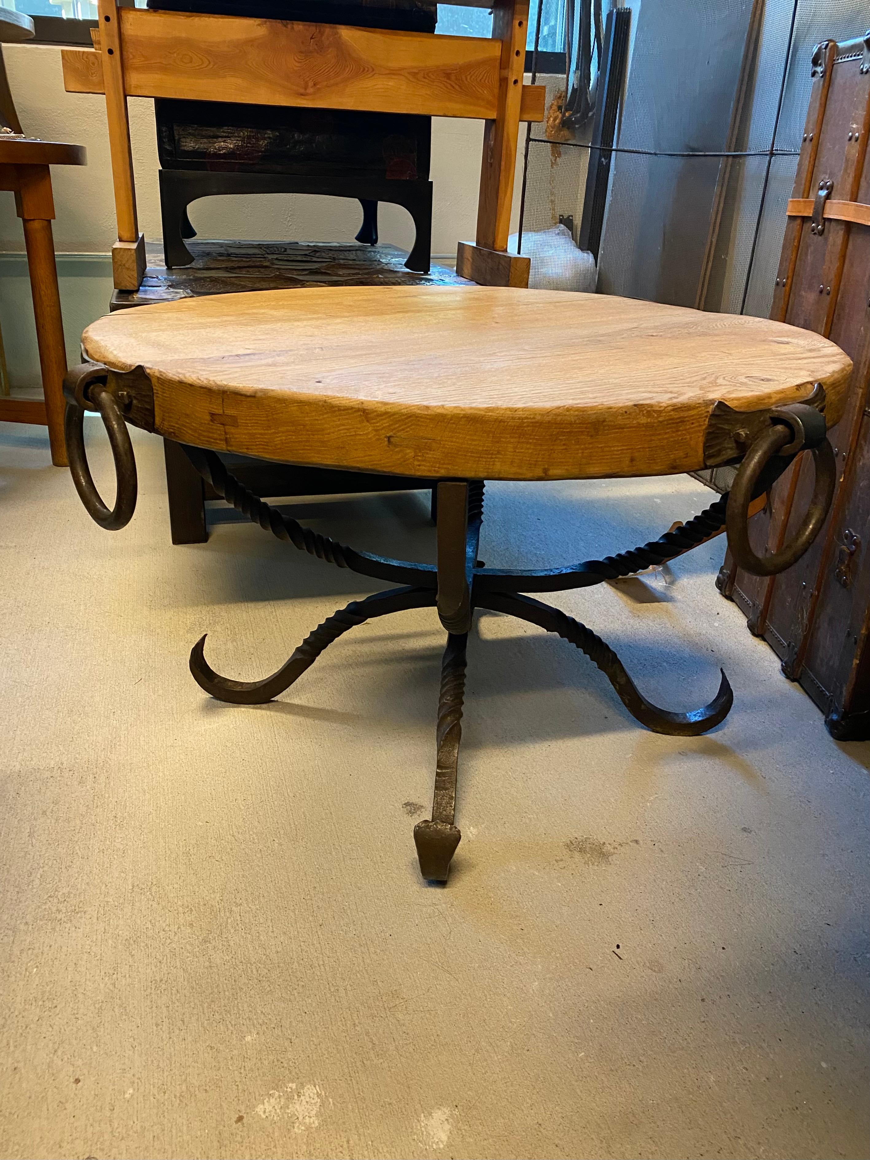 Heavy cocktail or side table with thick solid oak round top and forged iron base with well-scaled loop handles. Oak top is not stained and has natural wax finish. France, 1930-40's.