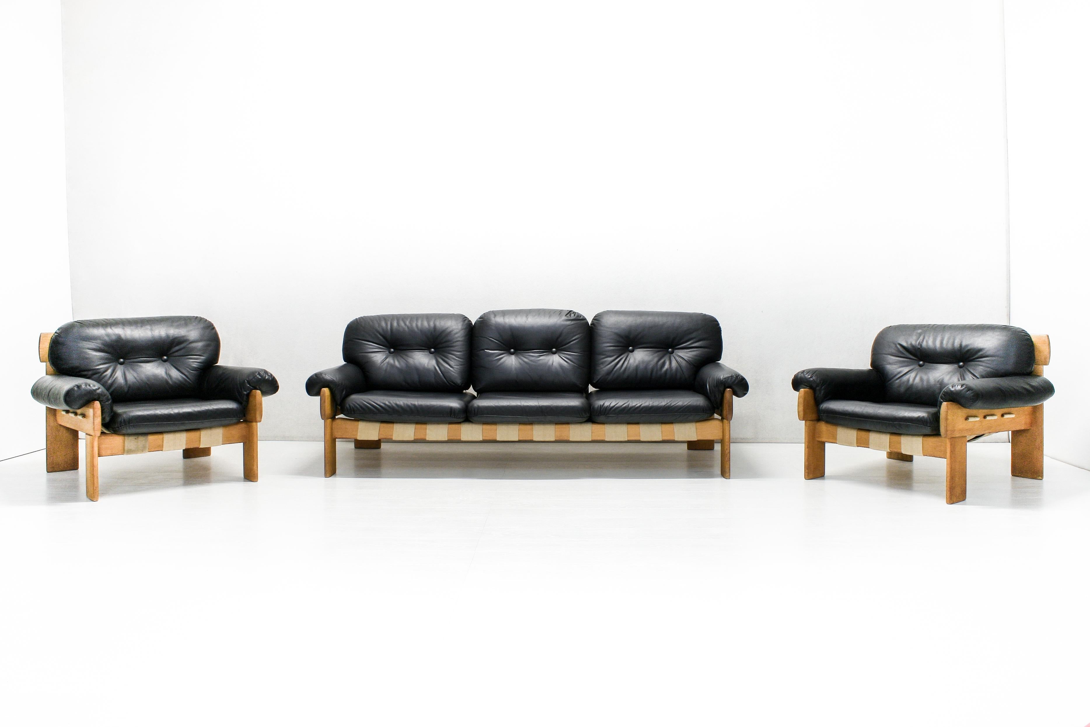 This living room set by Esko Pajamies for Asko, Finland was produced in the 1970s. A brutalist style oak frame with burlap straps embrace the soft black leather firm foam filled cushions.

The sofa measures 205 x 85 cm and the armchairs 80 x 85 cm.