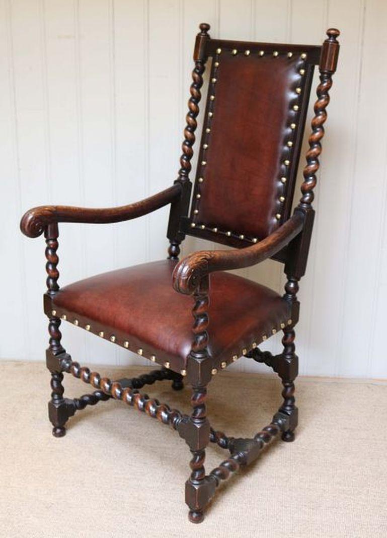 Oak and leather chair having barleytwist supports with carved shaped arms raised on turned legs reupholstered in leather with brass stud edges.