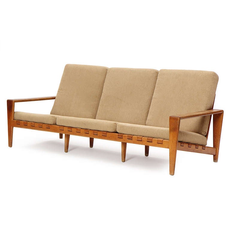 An outstanding Scandinavian Modern sofa. This sofa is constructed with a solid oak frame and leather straps supporting six upholstered cushions. Made in Denmark, circa 1950s.
