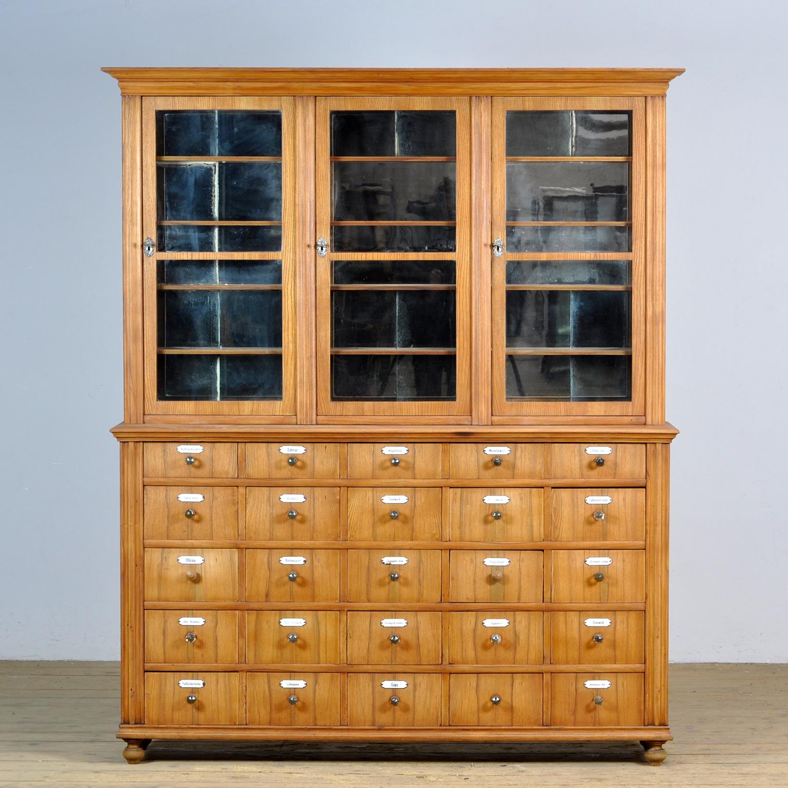 The cabinet is made of oak with drawers and back of pine wood. The cabinet consists of 2 parts. In the upper part there are three doors with the original antique glass. Behind each door are 4 shelves with a weathered mirror behind them. The mirror