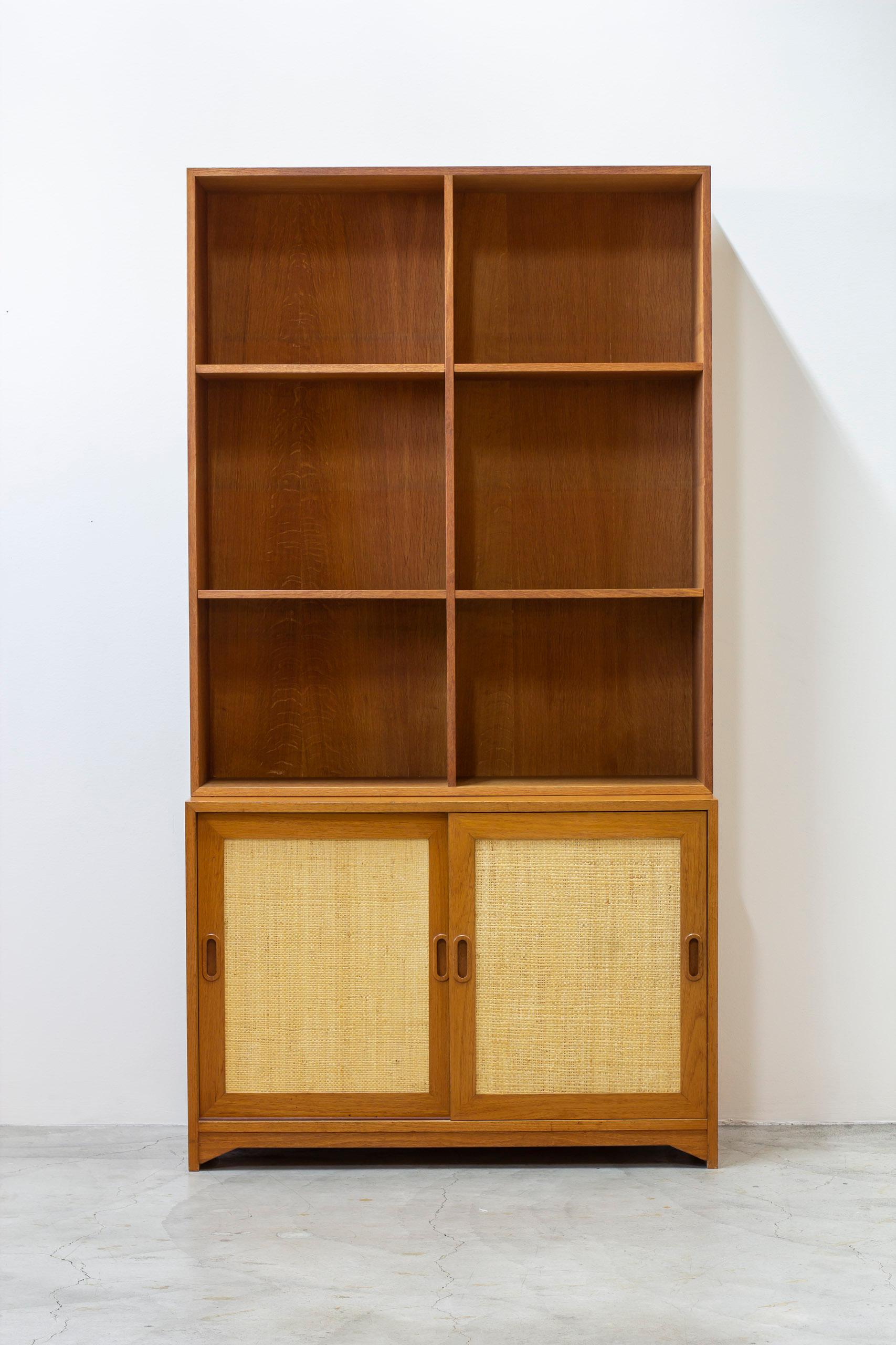 Libreria disegnata da Alf Svensson e prodotta negli anni '50 in Svezia da Bjästa Snickeri. Realizzata in teak nella parte della credenza con anta scorrevole in rattan. L'interno della credenza è realizzato in betulla chiara a contrasto. Lo scaffale