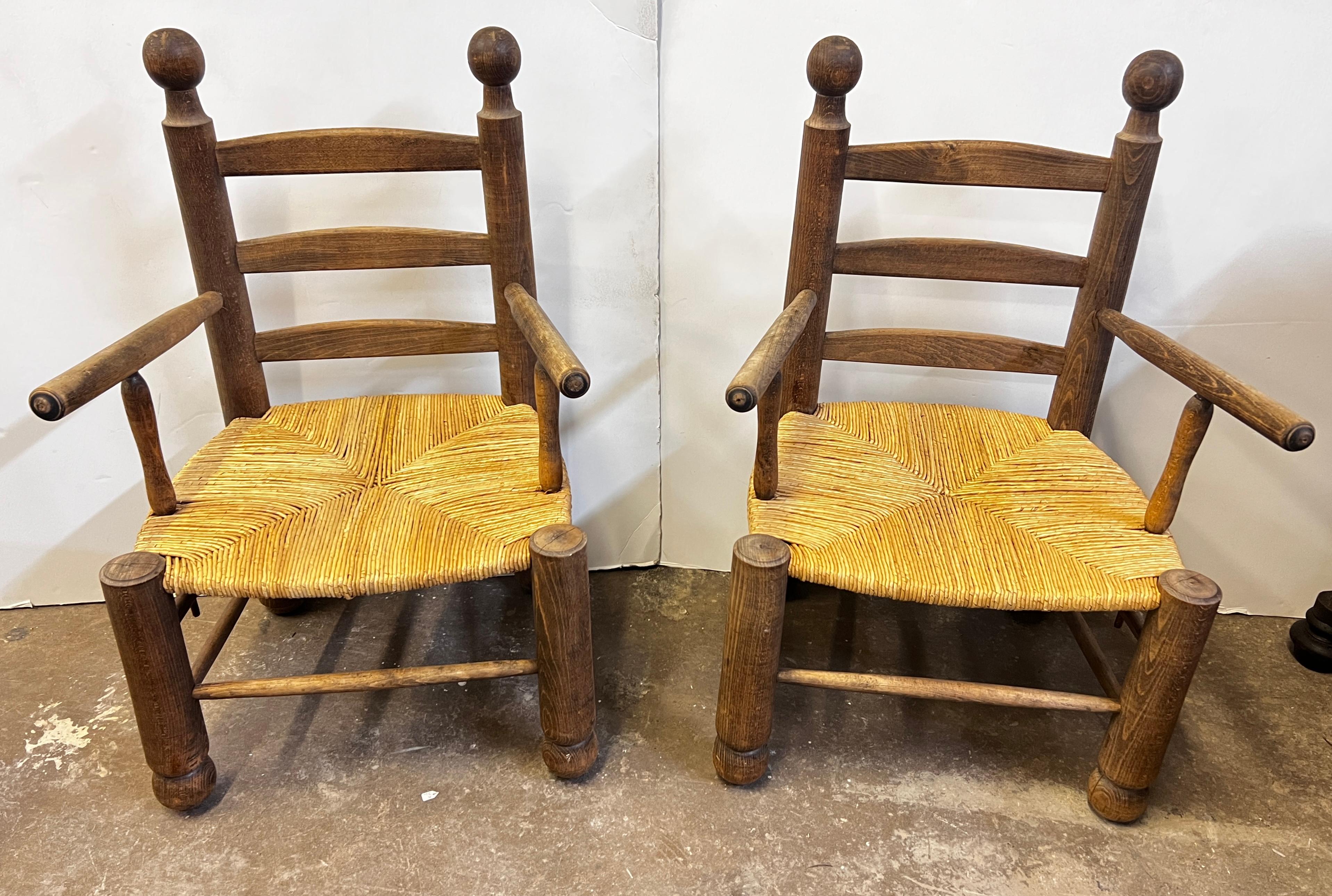 A beautiful patina pair of oak and rush French 1960s sturdy chairs attributed to Charles Dudouyt. This is a great pair to put in any design setting that can be placed by a fireside, sitting area, by a bed or hallway, etc. The options are endless.
