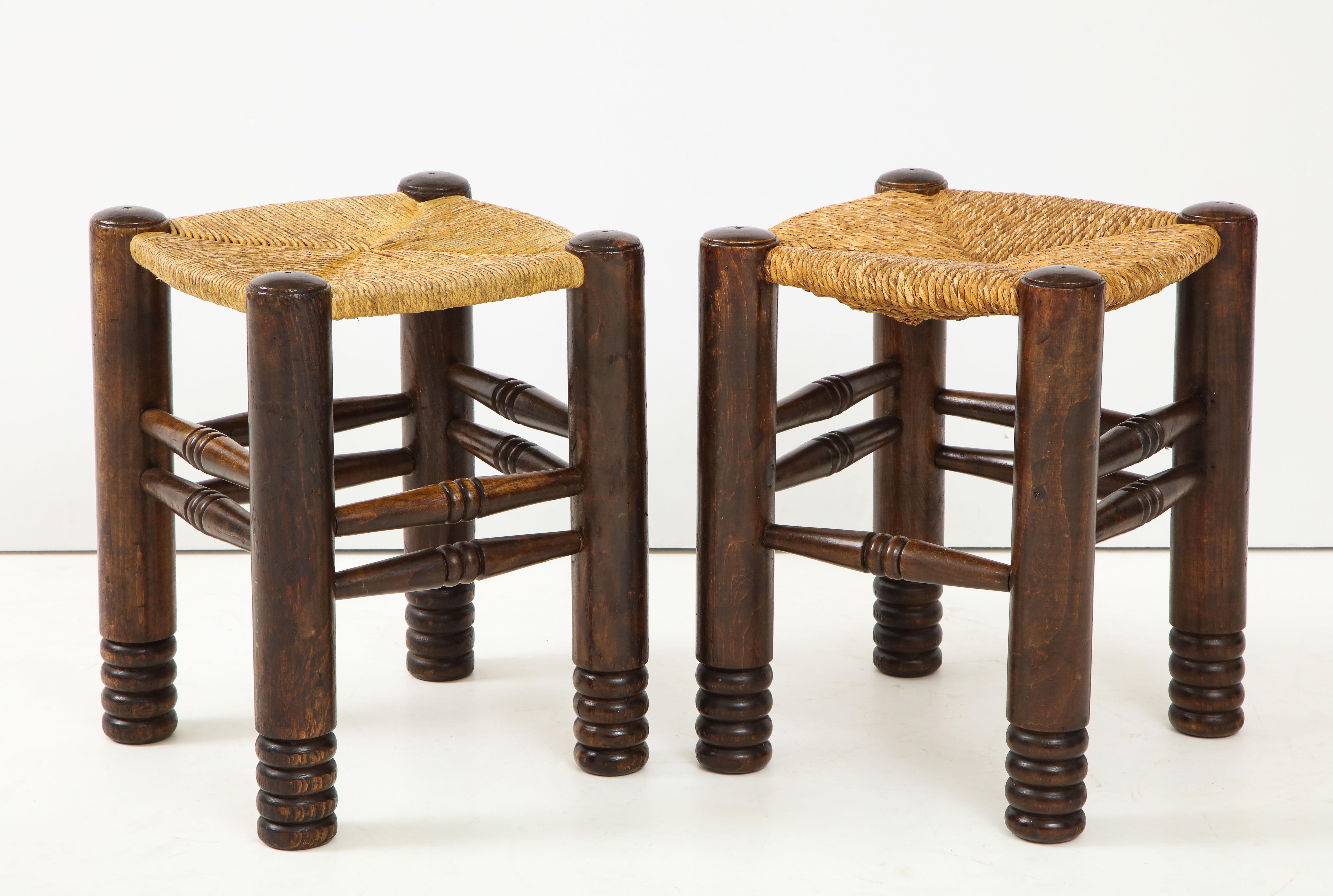 These rustic oak and straw stools designed by Charles Dudouyt in the 1930s are composed of 4 cylindrical solid oak legs linked by sleepers and a square braided straw seat. In excellent vintage condition, they have developed a beautiful patina over