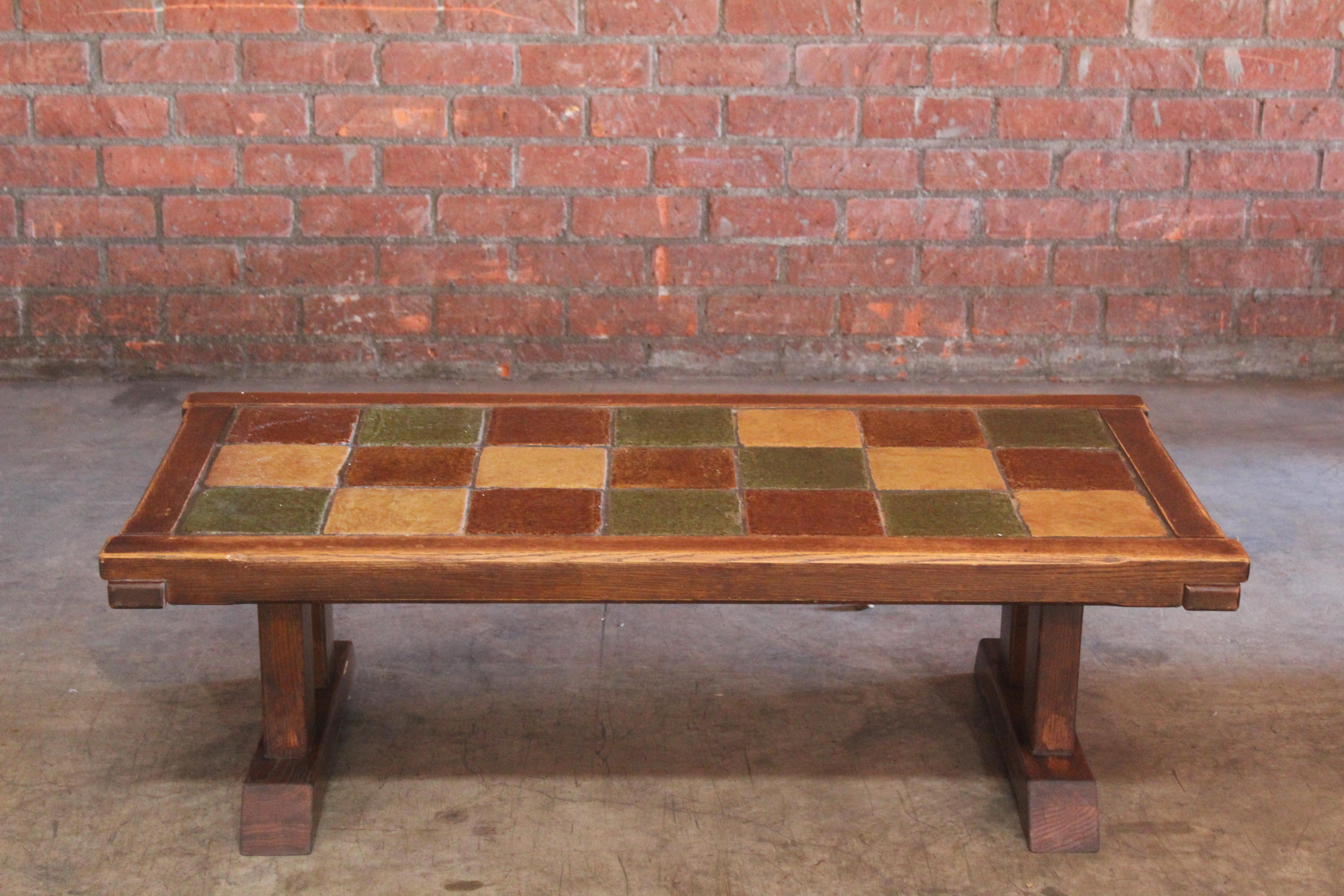 A vintage oak coffee table with glazed ceramic tiles from France circa 1950s. In good condition with some wear.