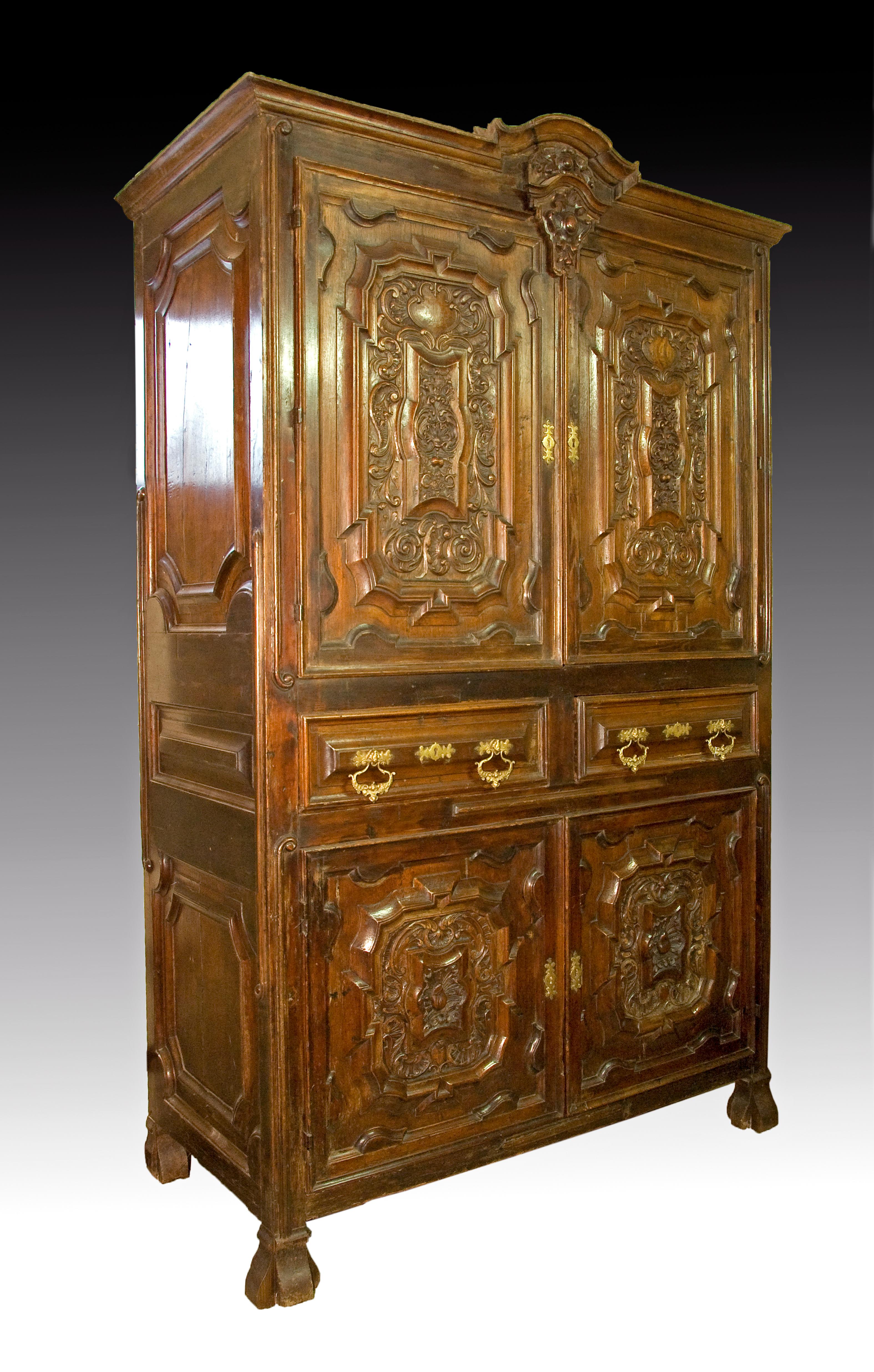 Cabinet made in oak and walnut, decorated with a profuse work of carving and molding. Of architectural structure inspired by the contemporary Baroque architecture, it is organized in two streets and three registers, and is topped by a cornice flown