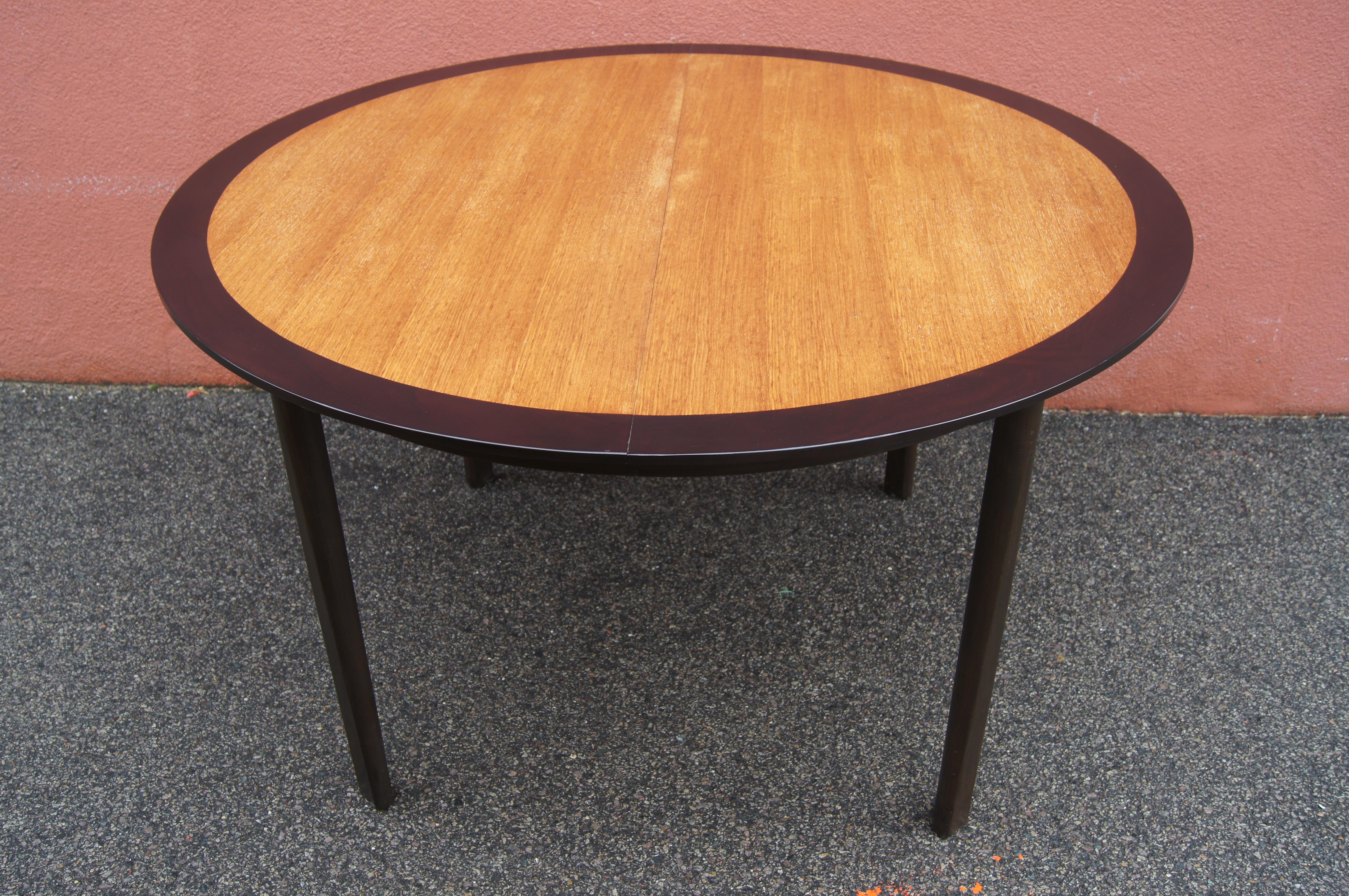 This handsome dining table by Roger Sprunger Dunbar features a wide band of ebonized walnut encircling honey-toned oak. Two 18-inch leaves allow the round table to expand to an oval of either 67.75 or 85.75 inches wide.

Metal Dunbar label