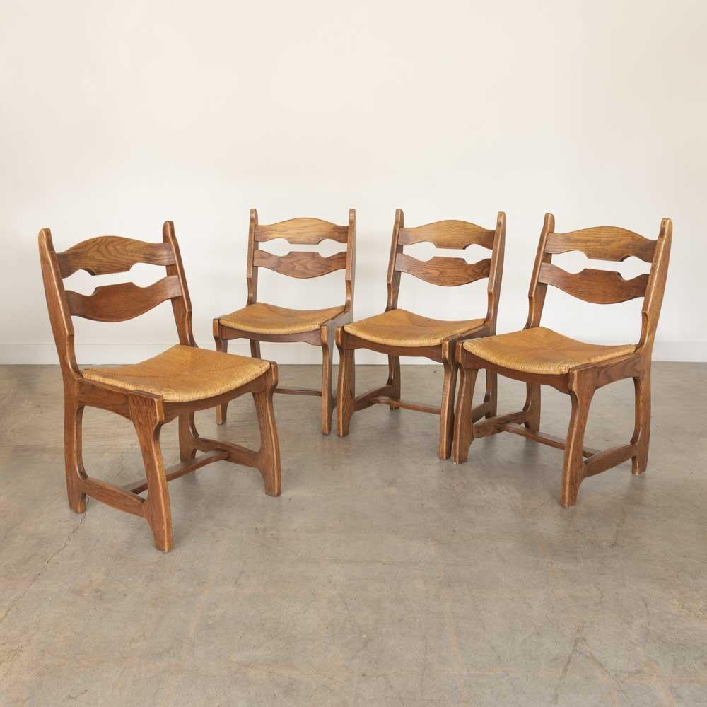 Splendido set di 4 sedie da pranzo in rovere massiccio con seduta originale in giunco intrecciato nello stile di Guillerme Chambron. Incredibile disegno a lama di rasoio sul retro. La sedia è in condizioni originali e presenta segni di usura e di