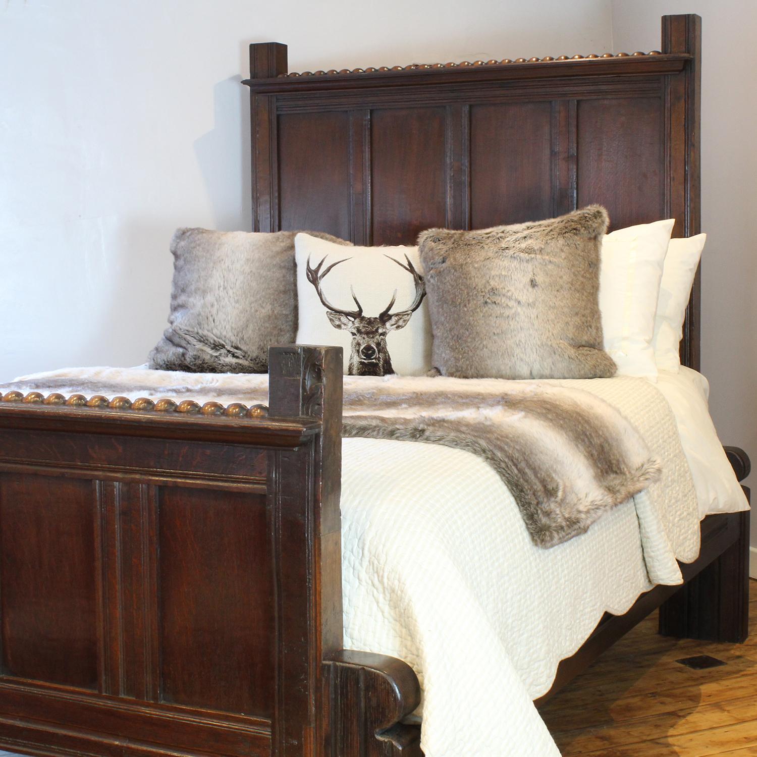 An exceptional oak bedstead with original panels dating as far back as the Eighteenth Century, with later alterations in the early Twentieth century. The panels may well have been from an oak four poster bed, with tall posts. In the early part of