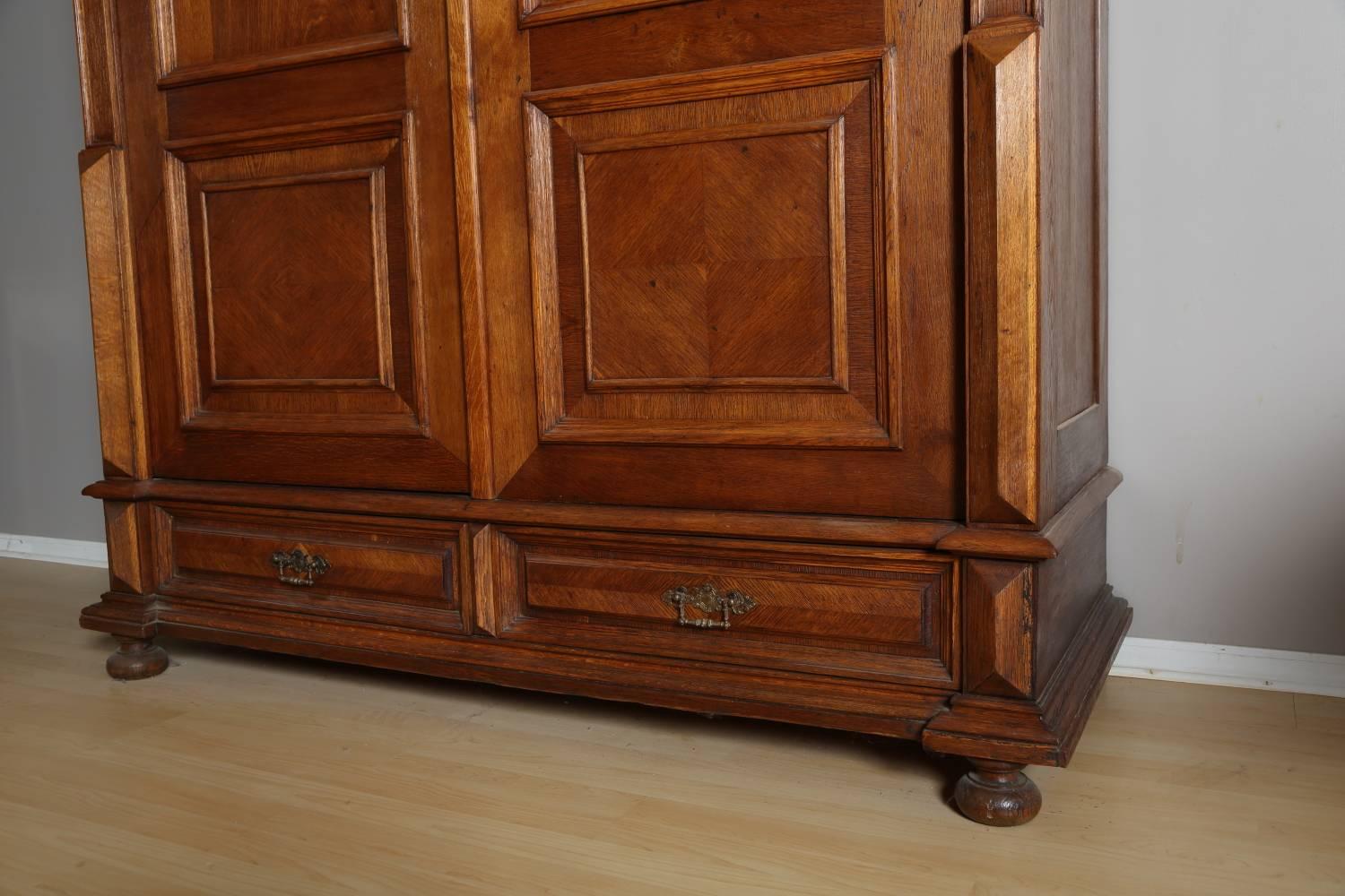 Oak armoire, circa 1880. Oak armoire crafted in Germany, features two doors flanked by carved details, and two drawers at bottom. The piece has been restored and waxed. The armoire comes apart for transportation. Complimentary delivery and set up