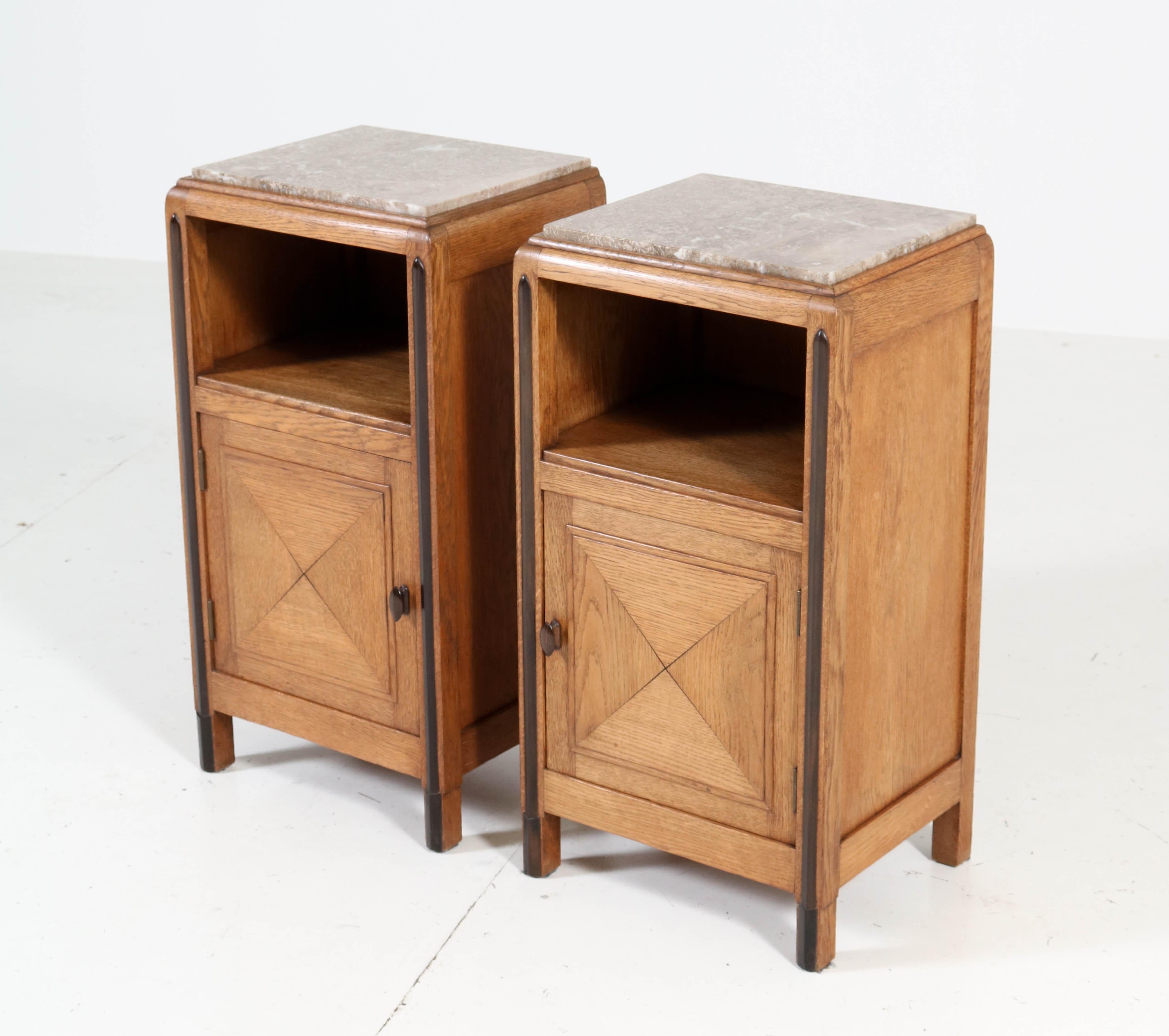 Wonderful and rare pair of Art Deco Amsterdam School nightstands.
Striking Dutch design from the 1920s.
Solid oak with solid ebony Macassar handles and lining.
The pair has the original marble tops and they are in very good shape.
In very good
