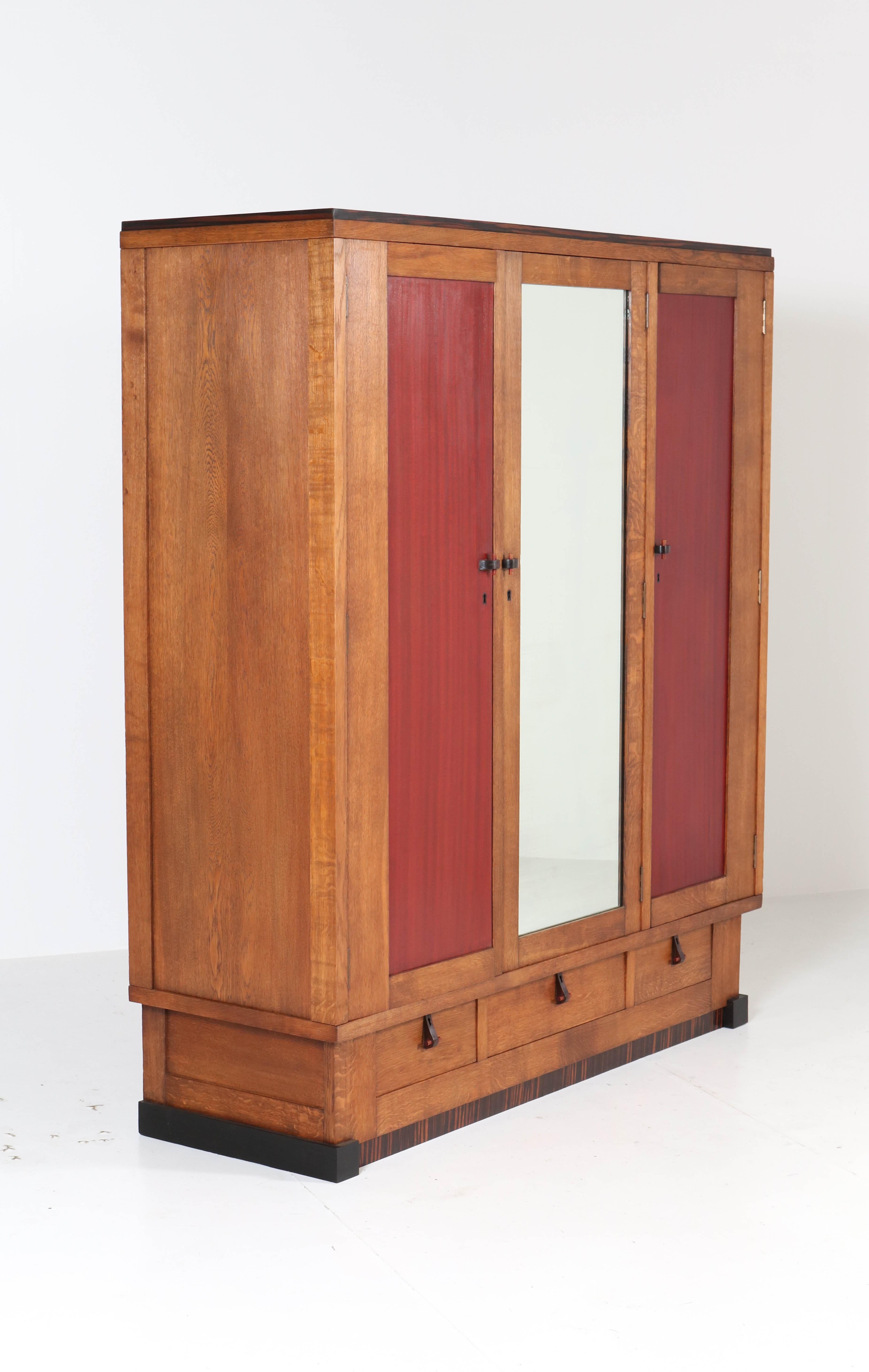 Magnificent and rare Art Deco Amsterdam School wardrobe or armoir.
Design by J.J. Zijfers Amsterdam.
Striking Dutch design from the twenties.
Solid oak with solid ebony Macassar handles and lining.
Behind the door with mirror, there are four