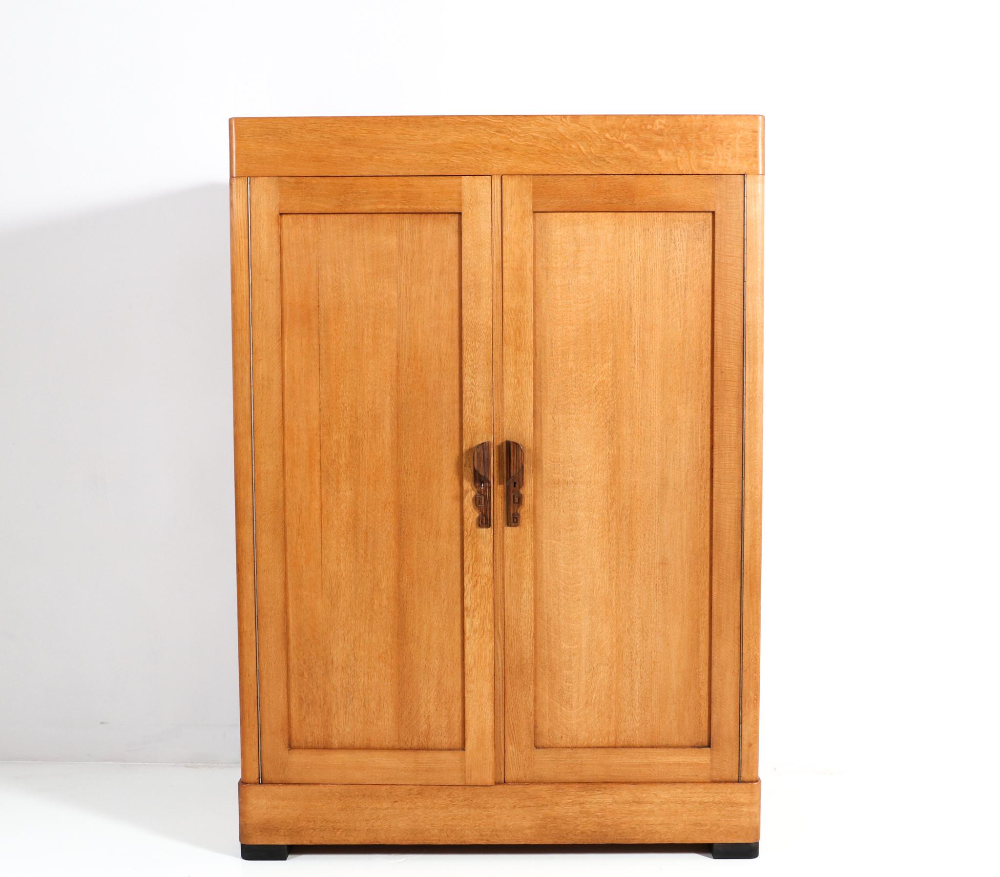 Stunning and rare Art Deco Amsterdamse School armoire or wardrobe.
Striking Dutch design from the 1920s.
Solid oak with stylish solid ebony macassar handles on both doors.
On the left side three original wooden shelves and one shelf with drawer,