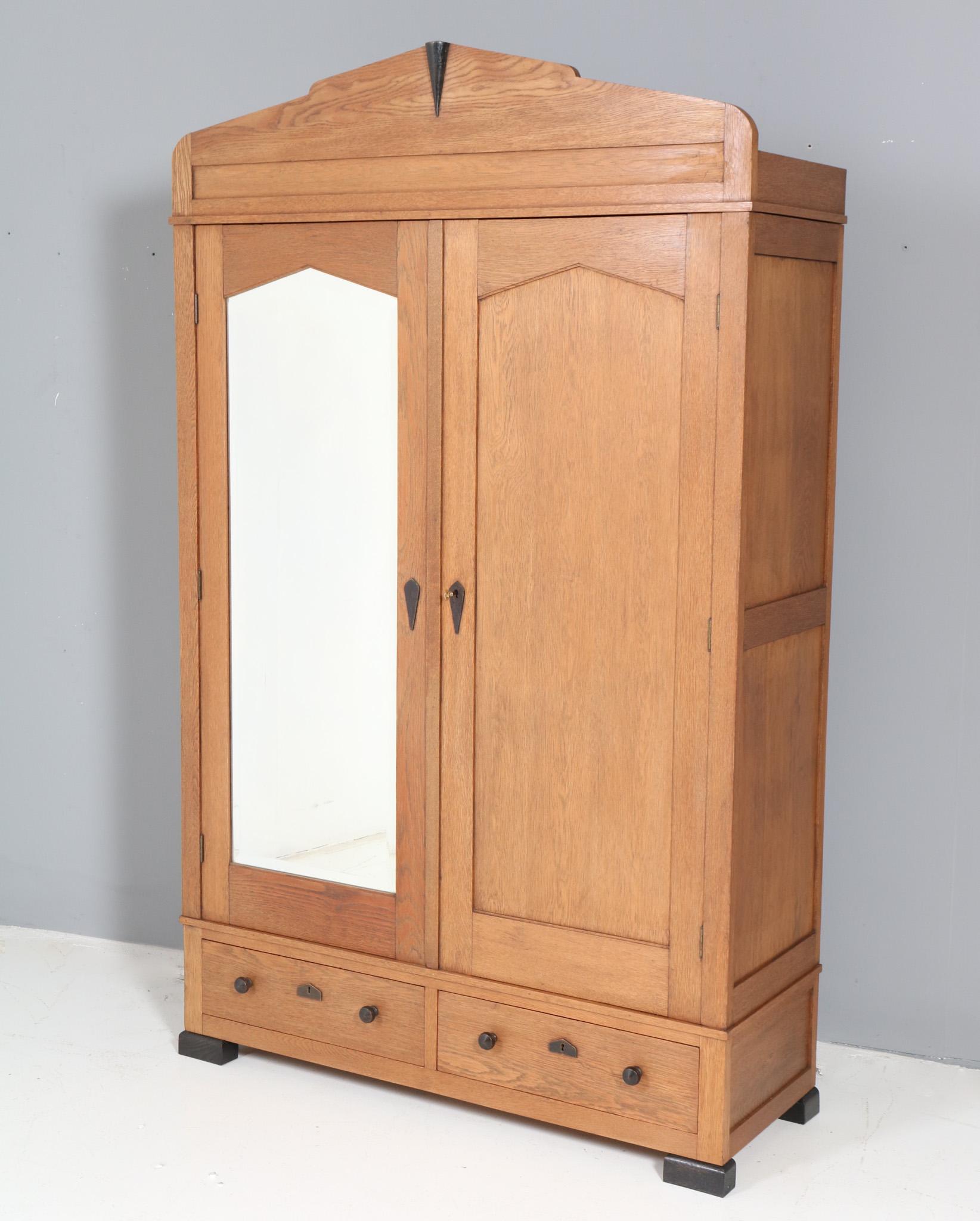 Stunning and rare Art Deco Amsterdamse School armoire or wardrobe.
Design by Fa. Drilling Amsterdam.
Striking Dutch design from the 1920s.
Solid oak with original black lacquered key entries and knobs on doors and drawer.
Original beveled mirror and