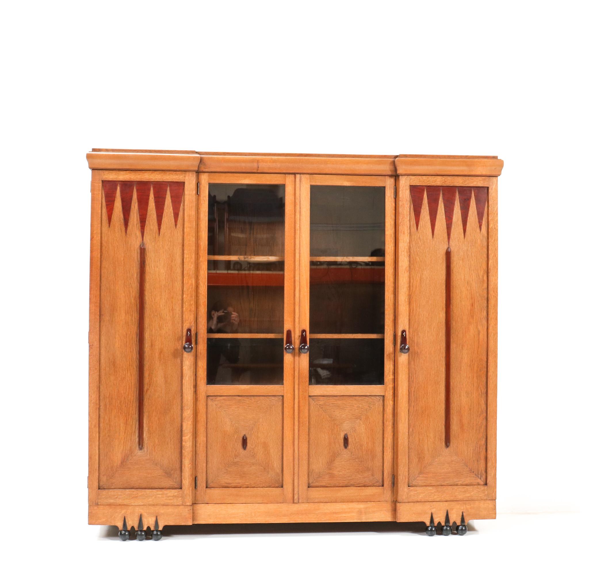 Magnificent and rare Art Deco Amsterdamse School bookcase.
Design by Max Coini Amsterdam.
Striking Dutch design from the 1920s.
Solid oak with original solid padouk knobs on the four doors.
The typical Amsterdamse School style of this unusual