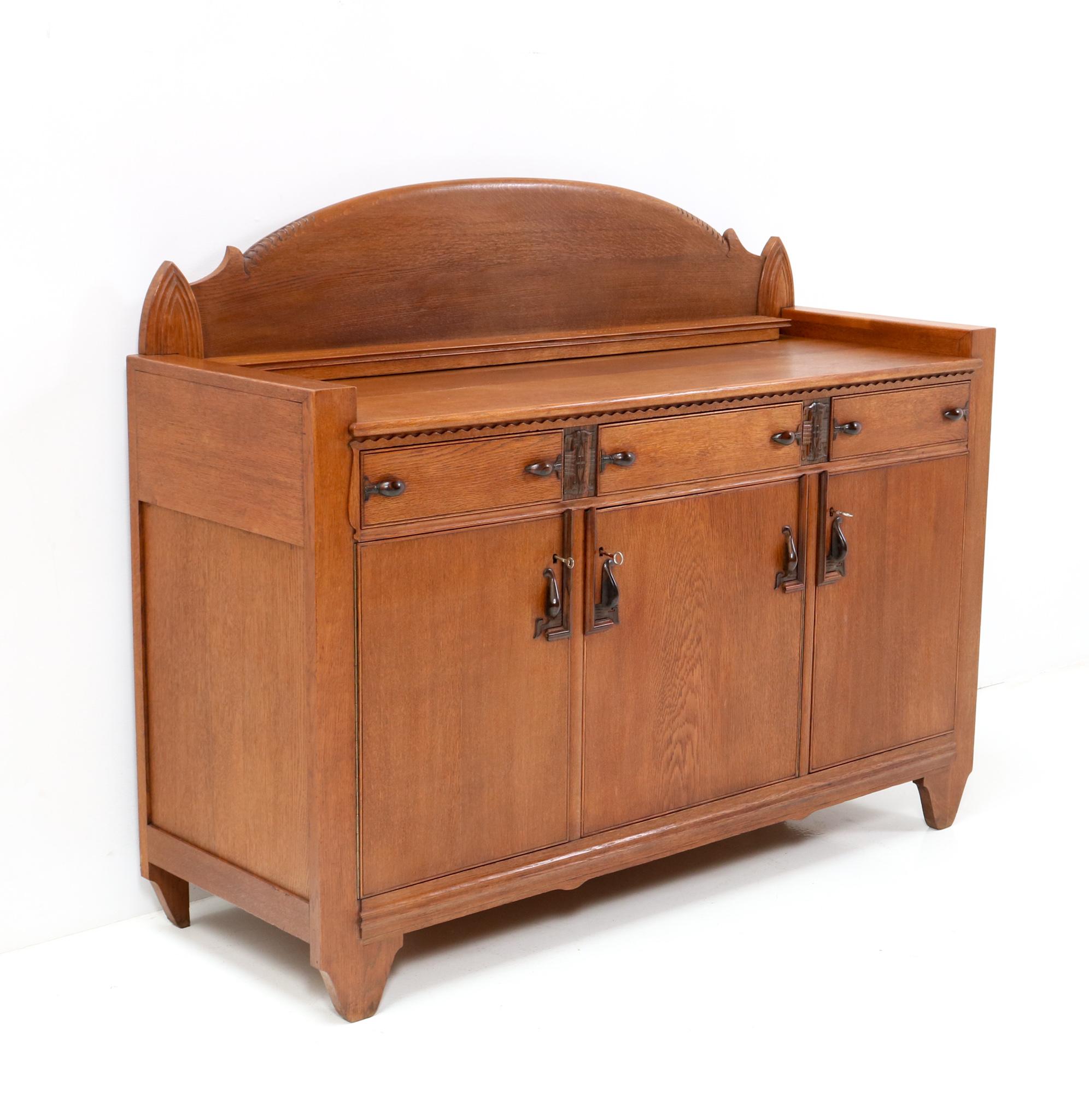 Magnificent and rare Art Deco Amsterdamse School credenza or sideboard.
Design attributed to Hildo Krop.
Striking Dutch design from the 1920s.
Solid oak and the doors are original with oak veneer.
The elegant and stylish hand-carved handles on doors